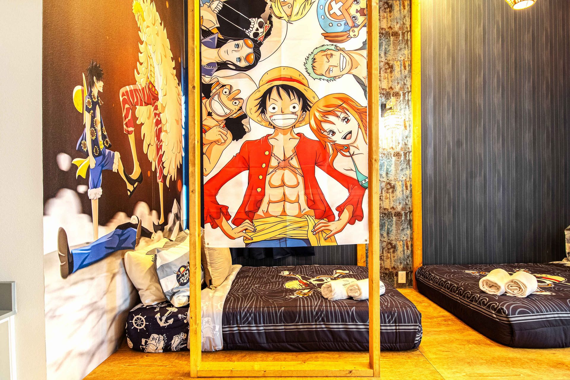 Cozy anime-themed room with vibrant One Piece decor and comfortable floor beds.
