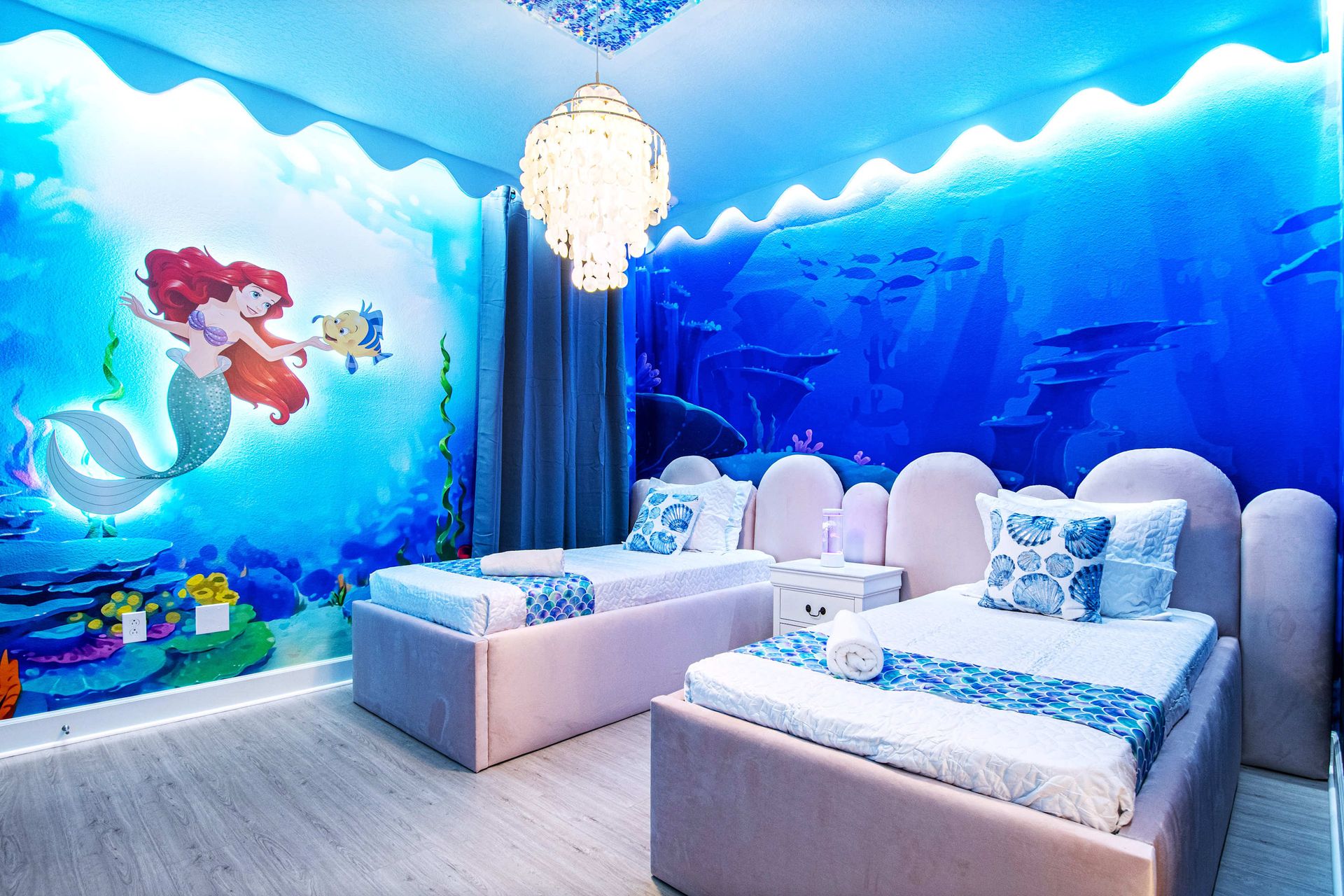 Underwater-themed bedroom with mermaid mural, soft lighting, and whimsical charm
