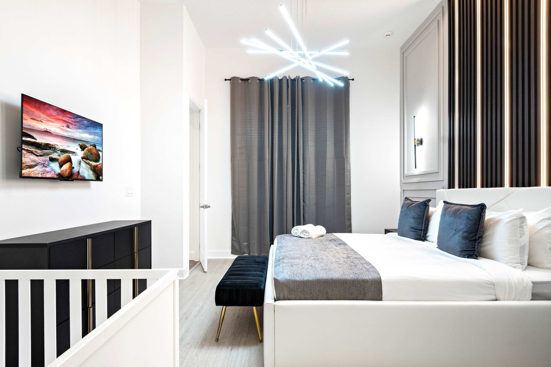 Chic modern bedroom with sleek lighting, upscale decor, and a spa-like ensuite
