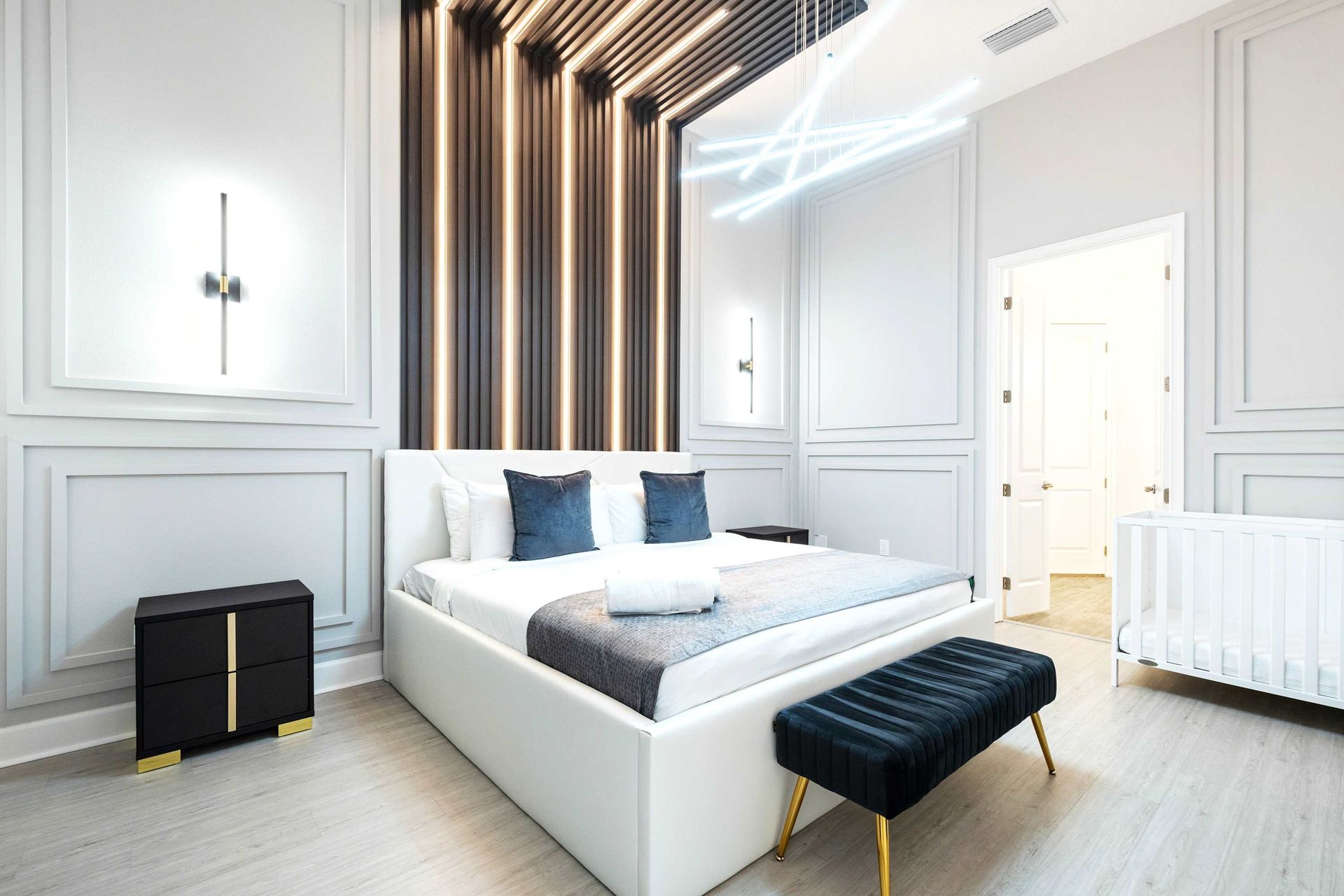 Chic modern bedroom with sleek lighting, upscale decor, and a spa-like ensuite
