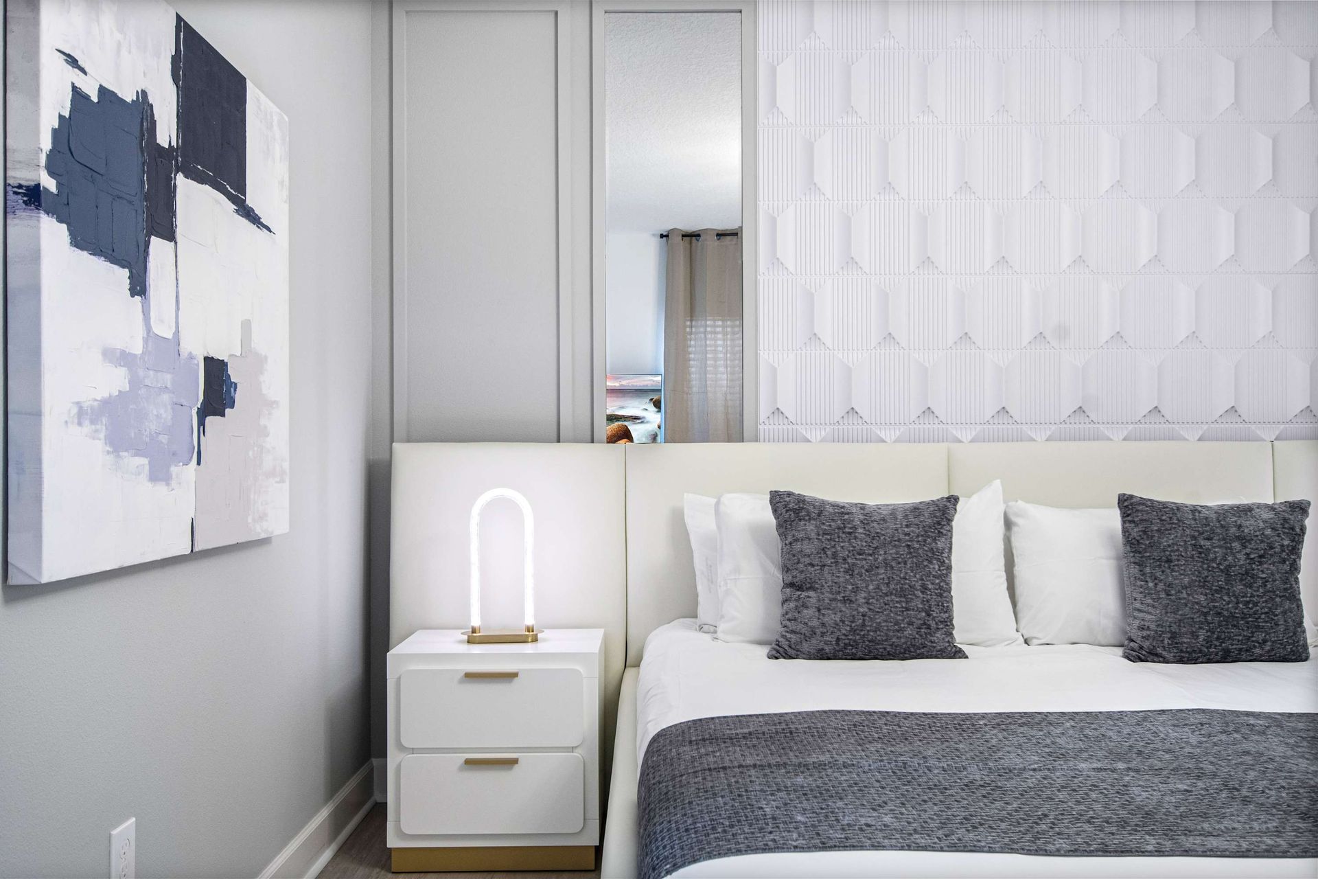 Bright and modern bedroom with textured accent wall, cozy king bed, and chic decor
