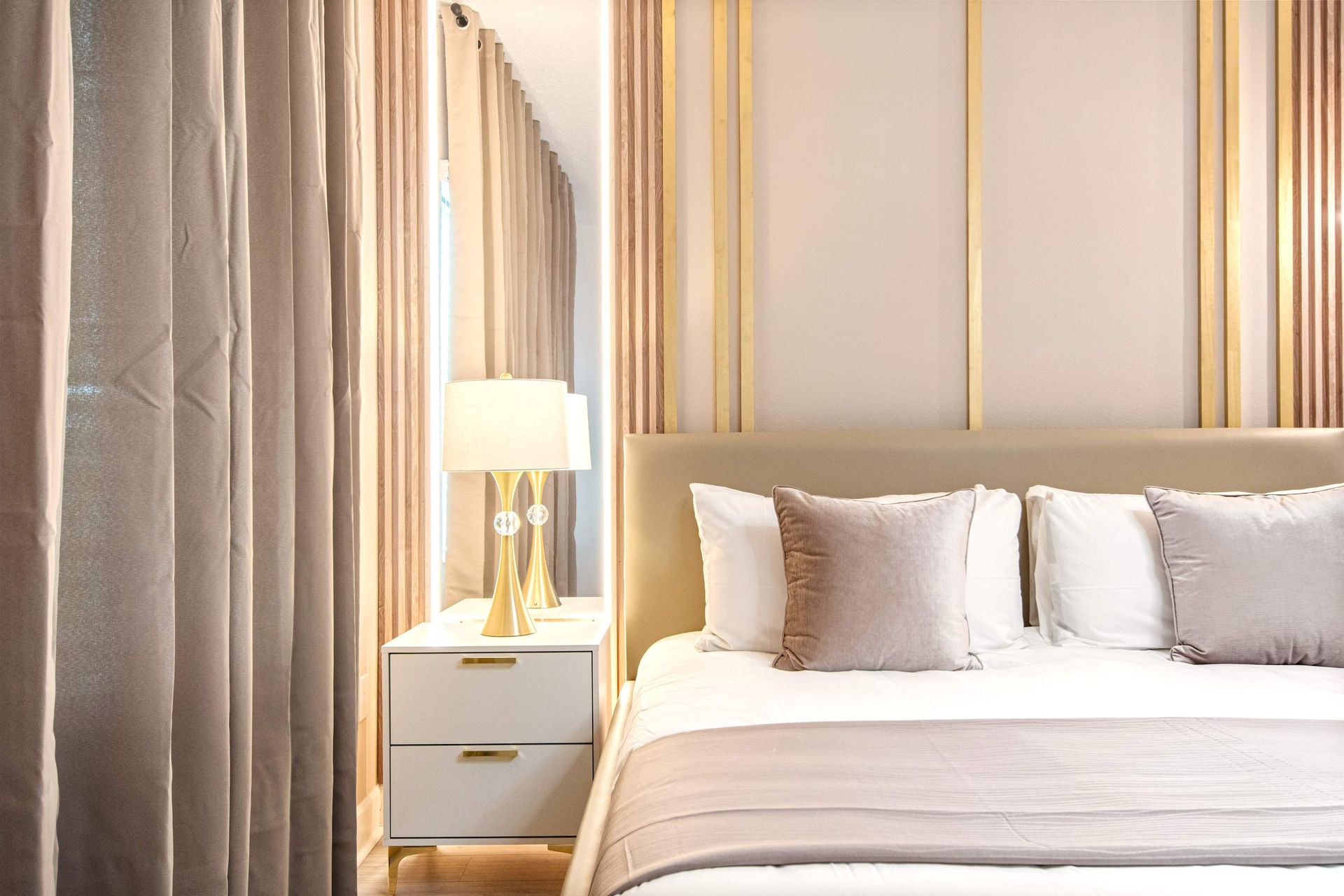 Luxurious bedroom with gold accents, plush bedding, and elegant draped curtains
