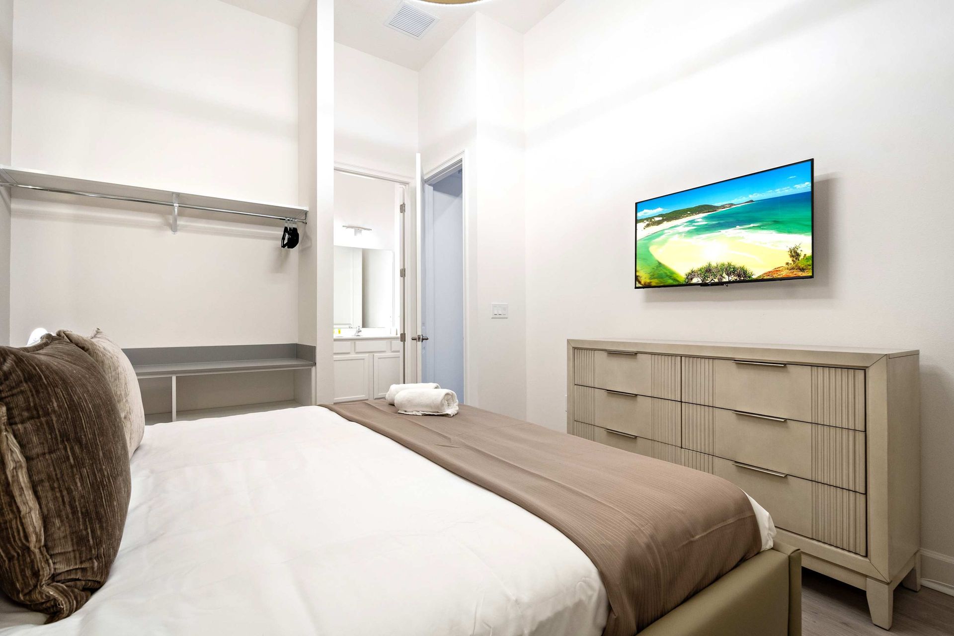 Elegant bedroom with modern chandelier, plush king bed, and private ensuite bath
