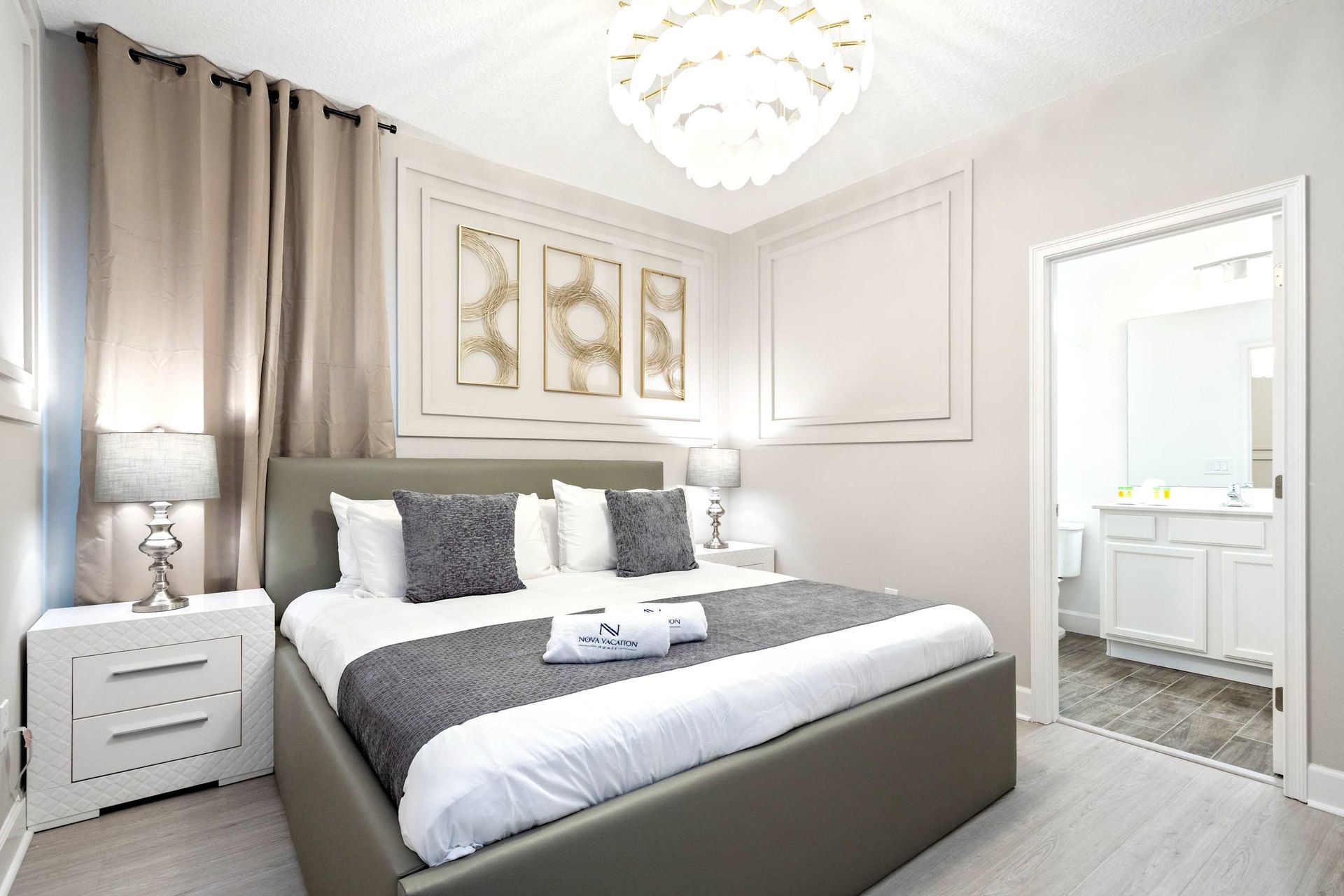 Elegant bedroom with modern chandelier, plush king bed, and private ensuite bath

