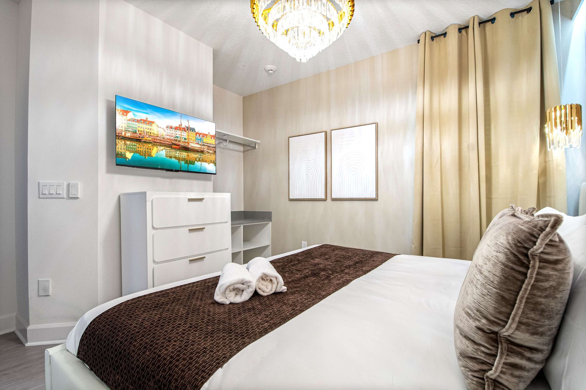 Cozy upscale bedroom with wall-mounted TV, elegant lighting, and modern decor
