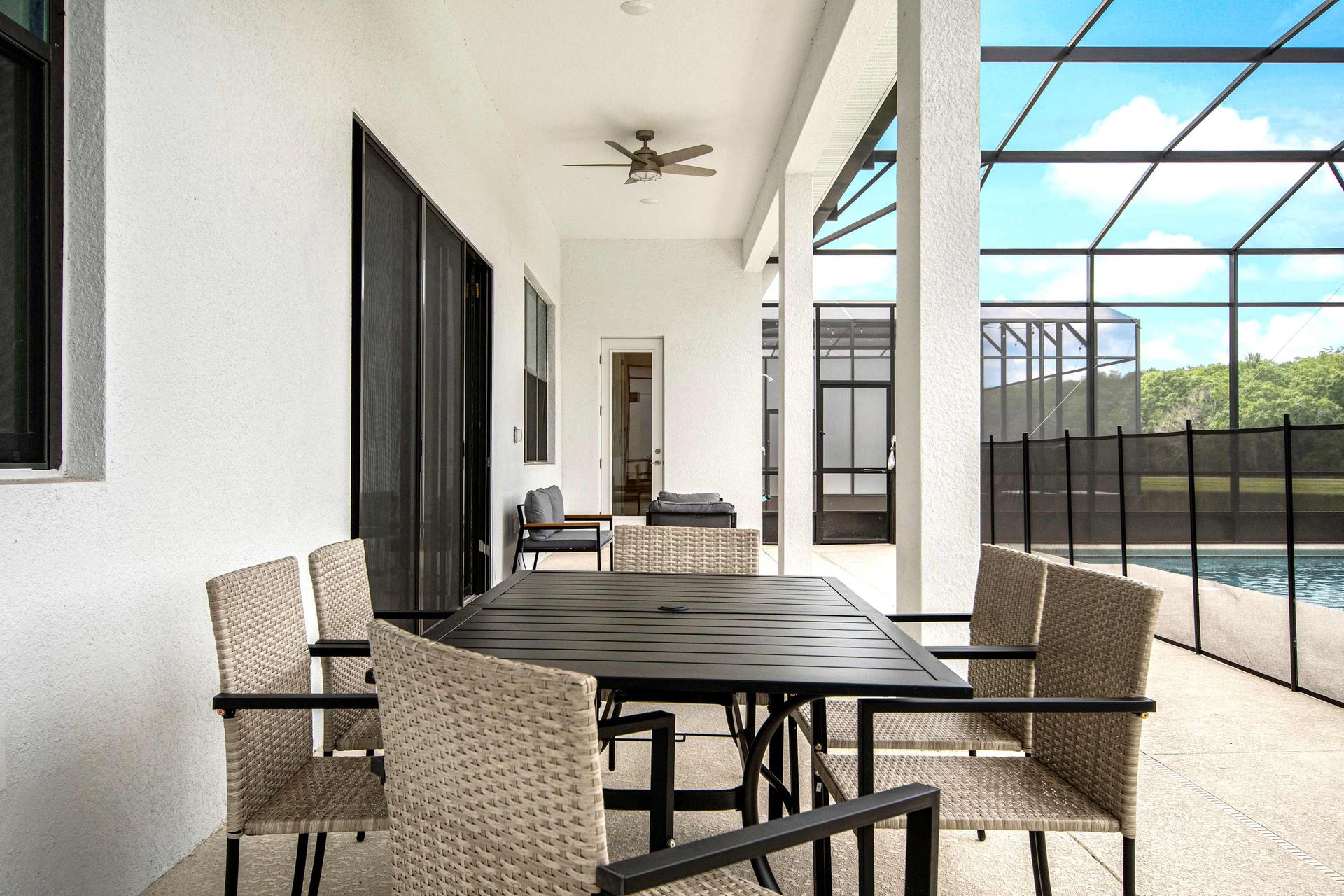 Spacious screened patio with pool, dining area, lounge chairs, and nature views
