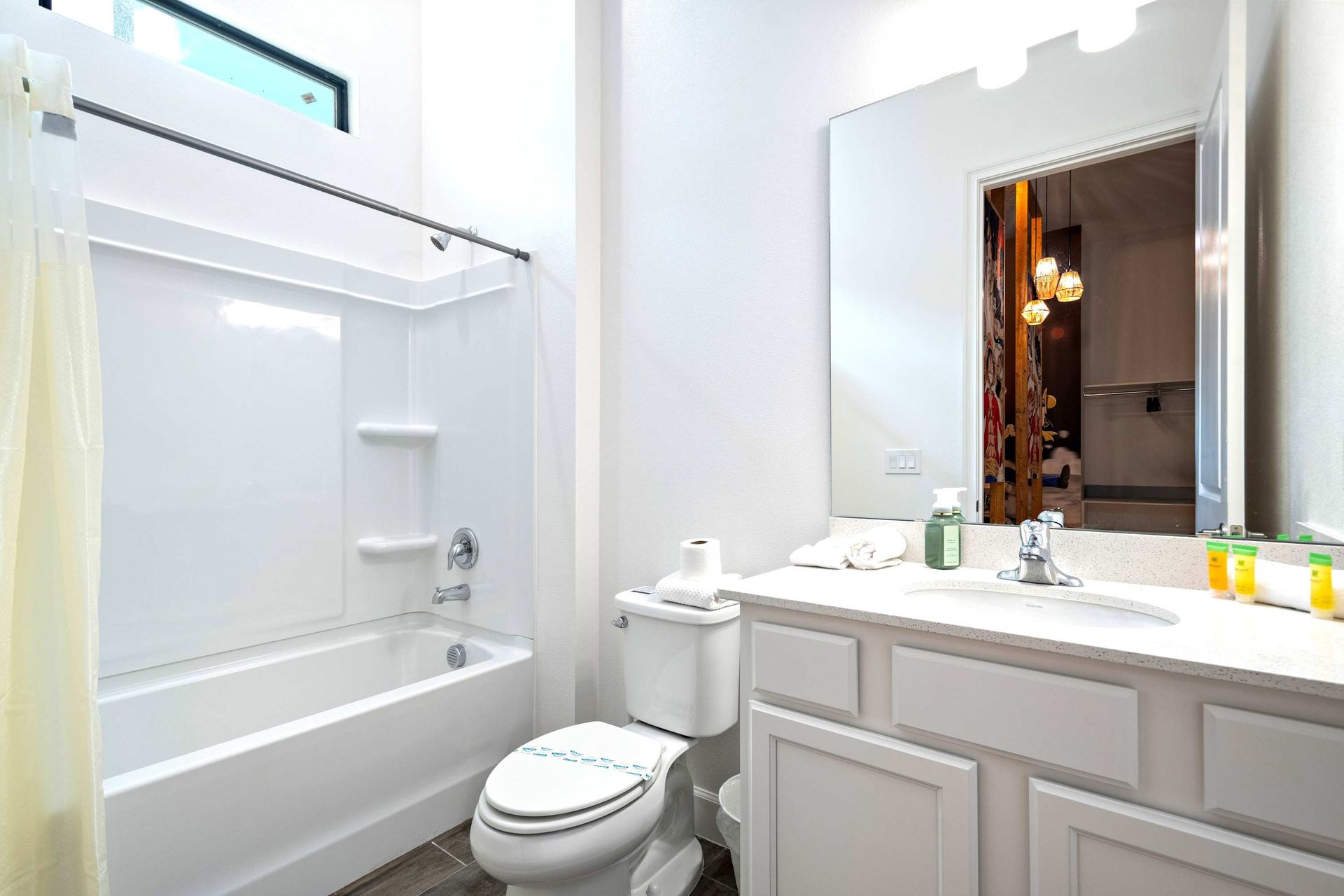 Bright and clean full bathroom with tub, large mirror, and modern white finishes
