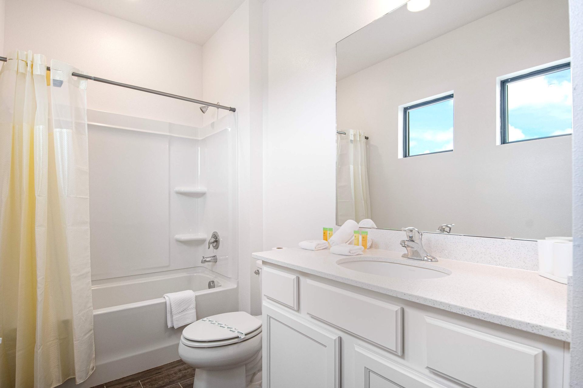 Modern full bathroom with bright white finishes, tub-shower combo, and essentials
