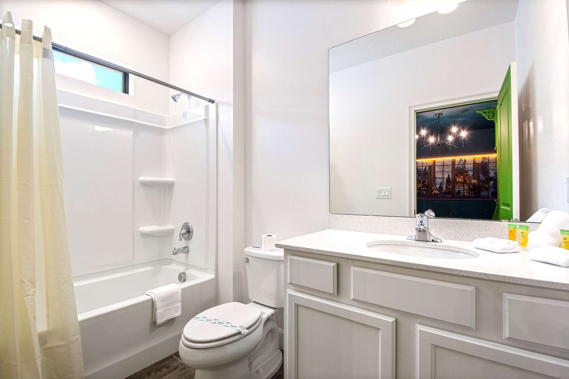 Clean and bright bathroom with tub, large vanity, and natural light above shower
