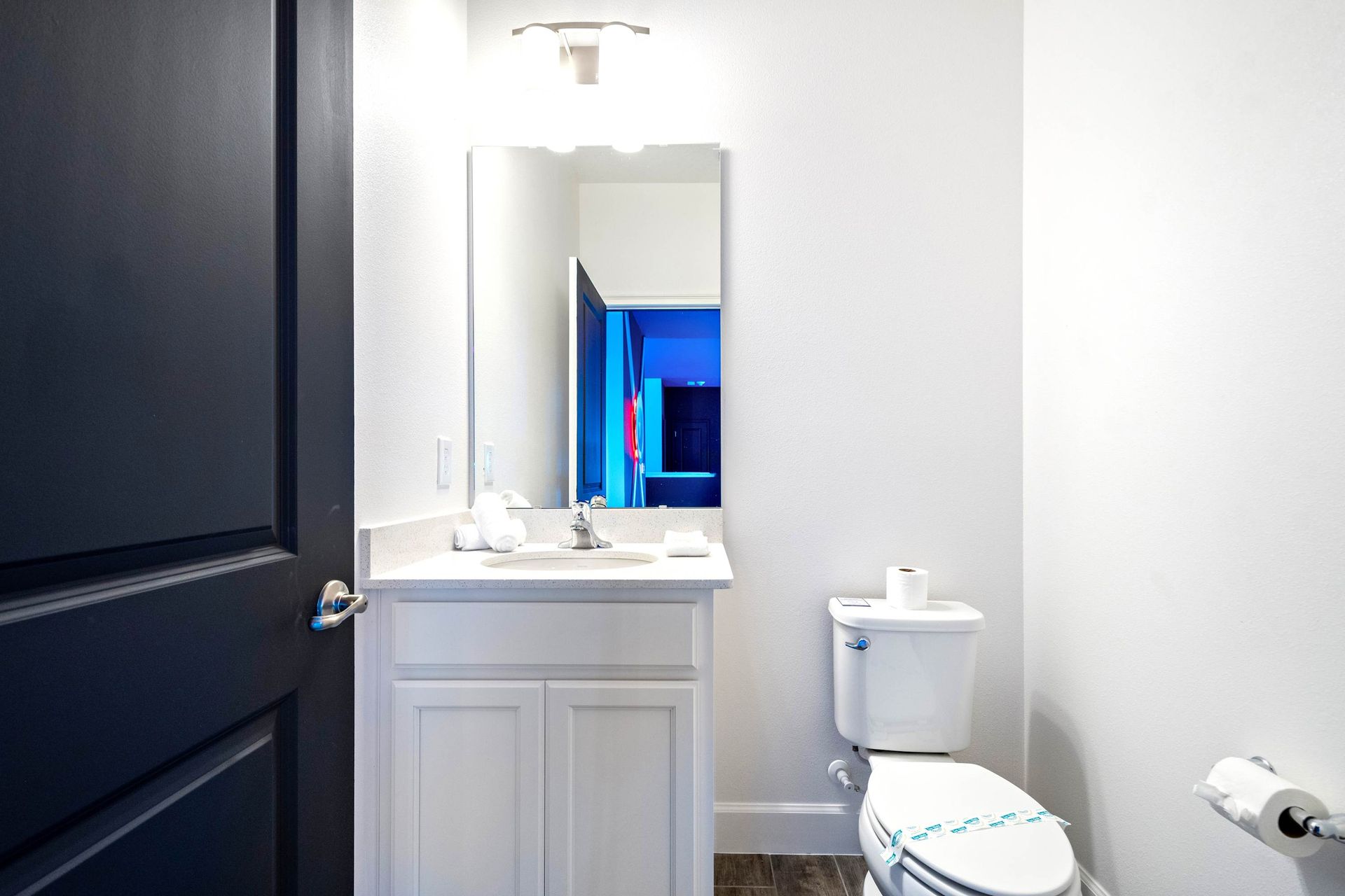 Cozy half bath with sleek vanity, bright lighting, and modern minimalist style
