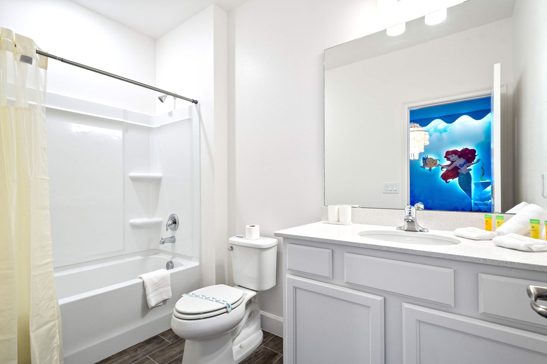 Playful full bathroom with tub-shower combo, bright vanity, and themed wall art
