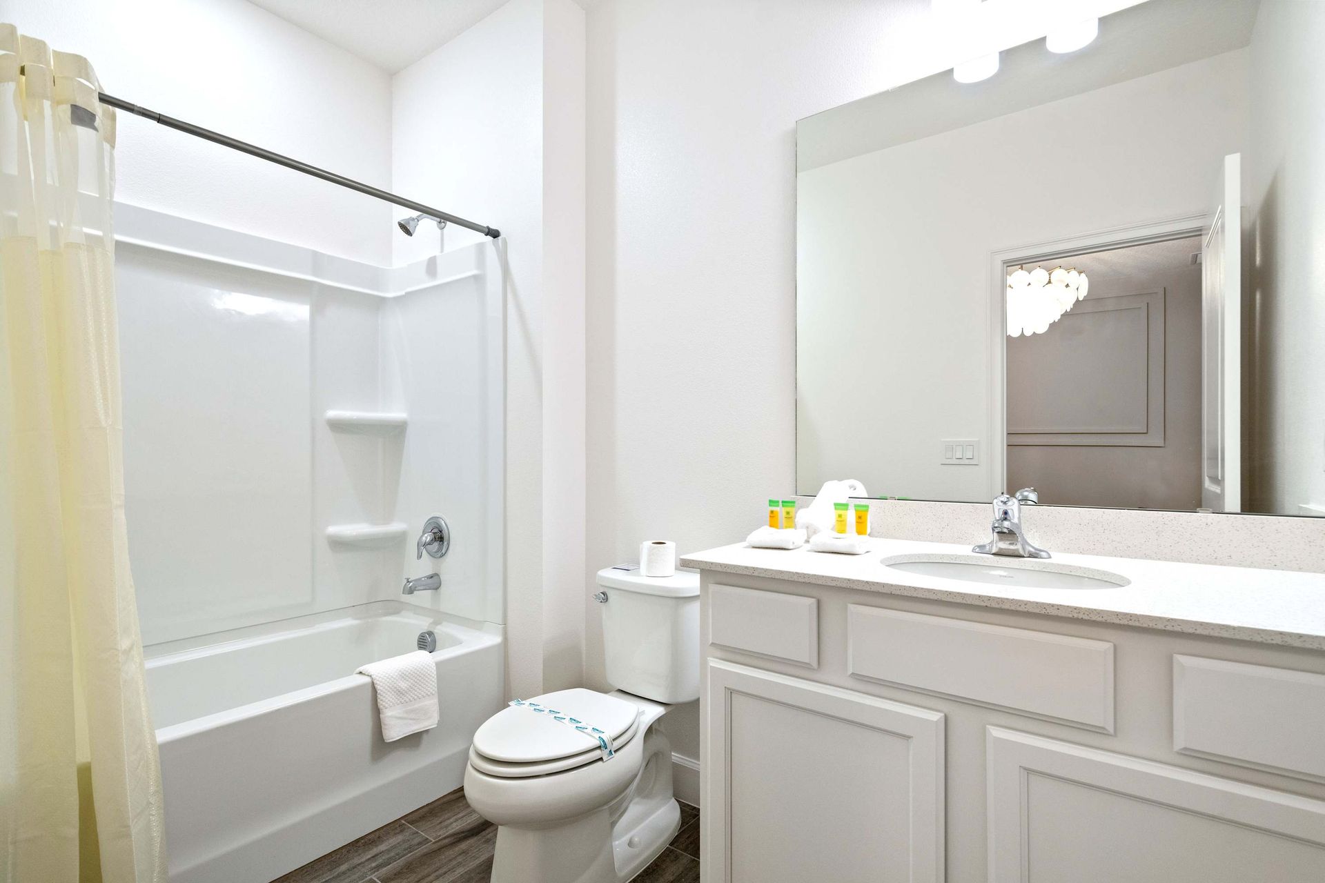 Fresh and bright full bathroom with tub, large mirror, and clean modern design
