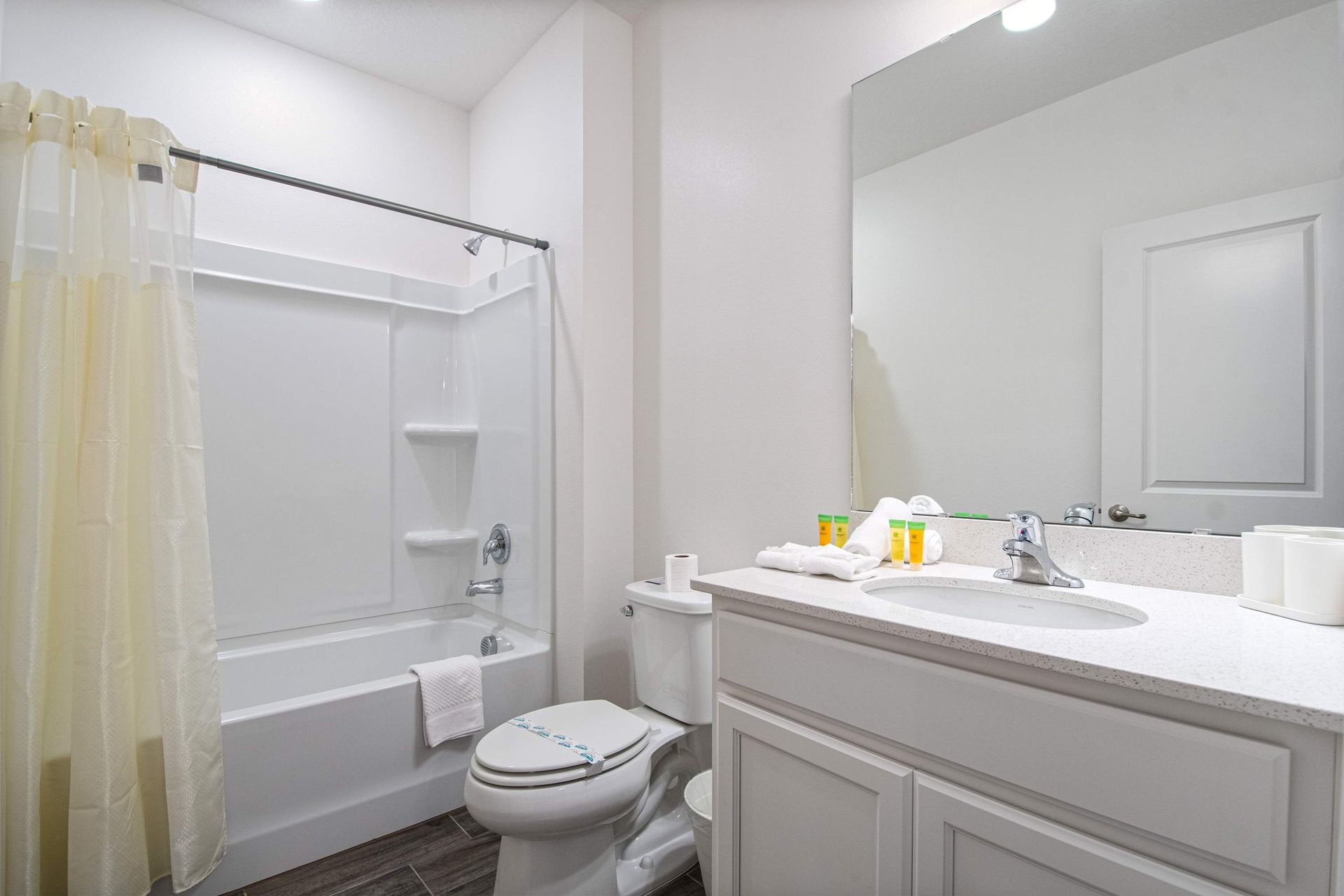 Fresh and bright full bathroom with tub, large mirror, and clean modern design

