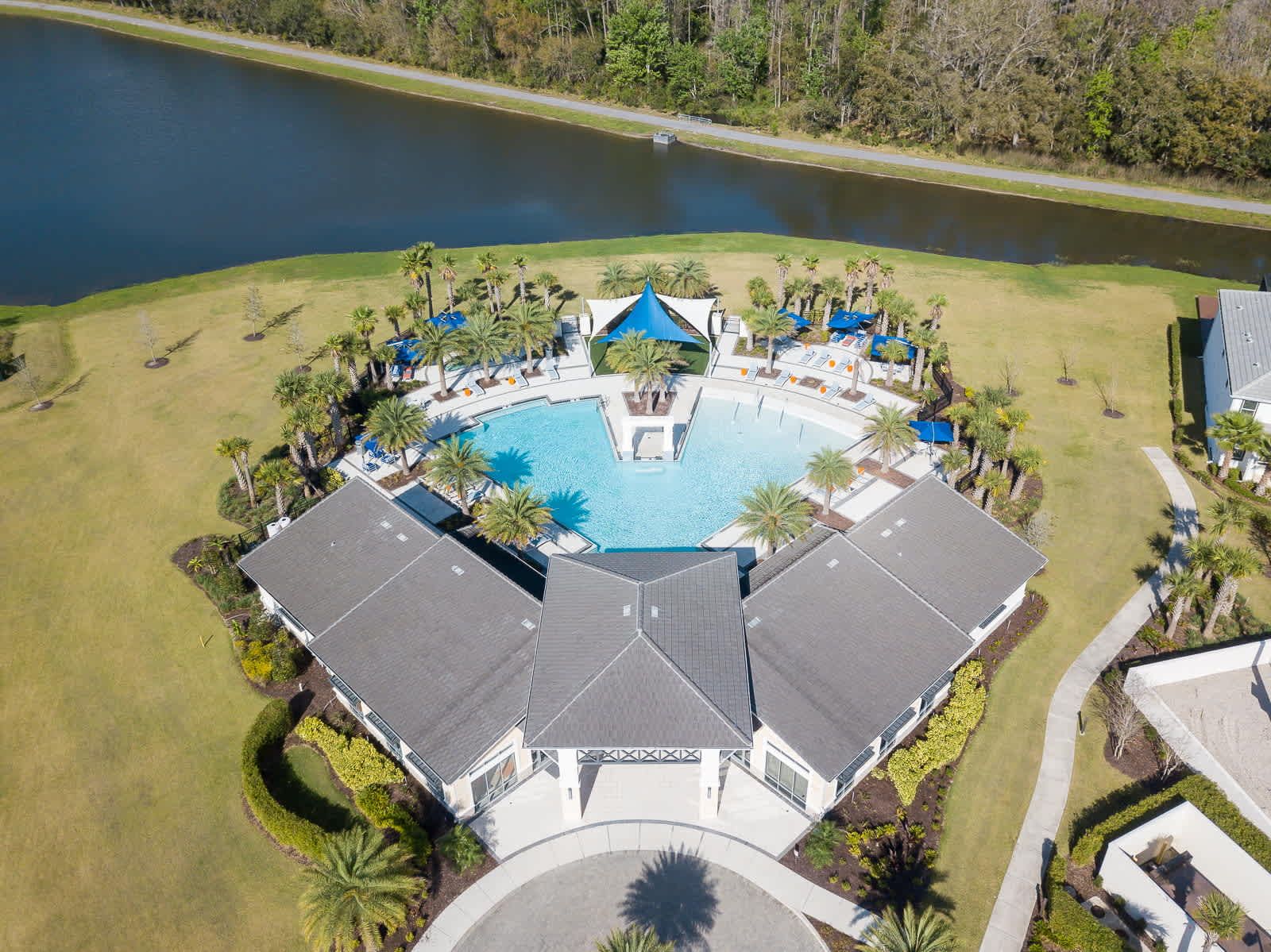 Luxurious villa with expansive pool, lush palms, serene lakefront tranquility.
