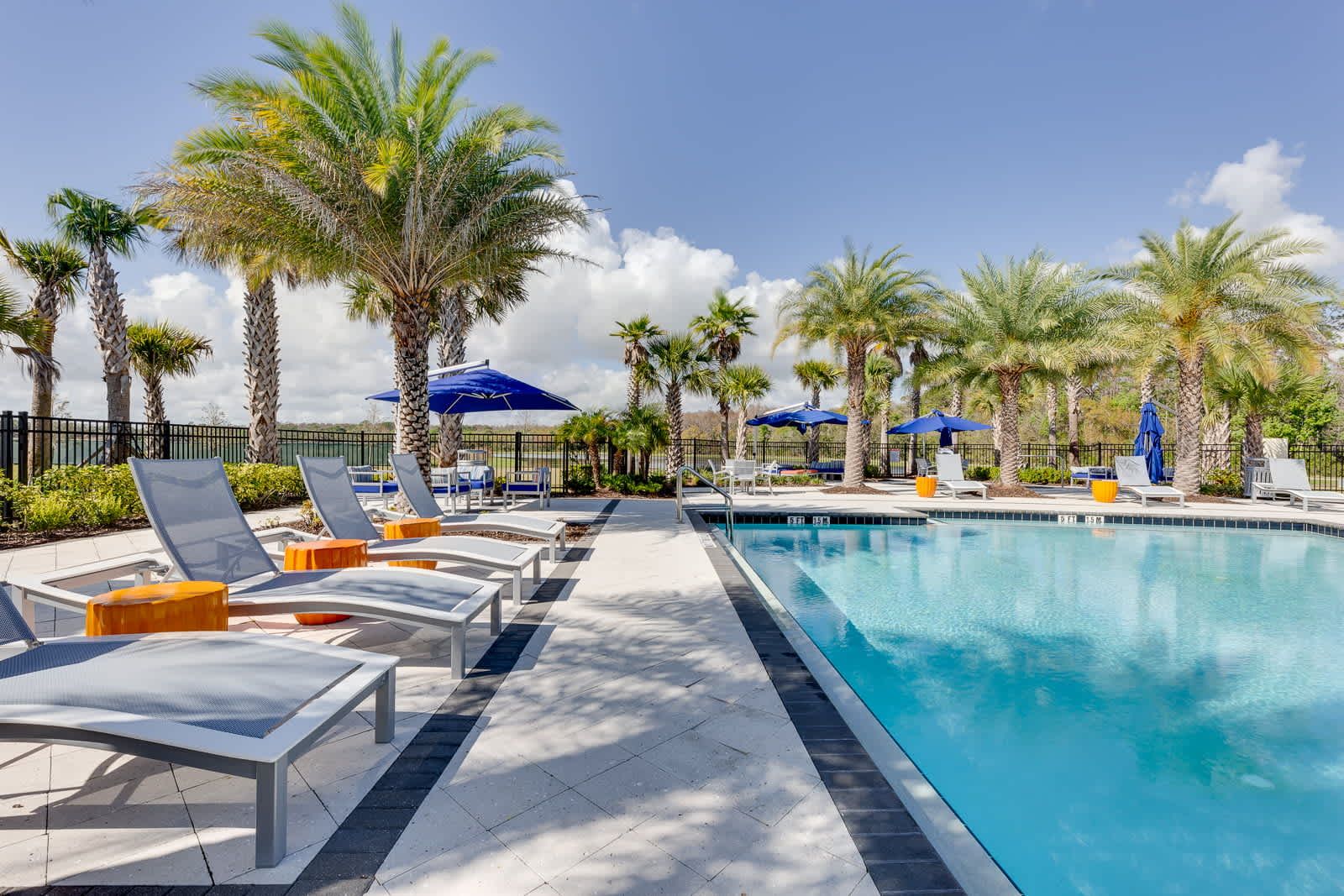 Relax poolside under palms, stylish loungers, serene tropical vacation escape.

