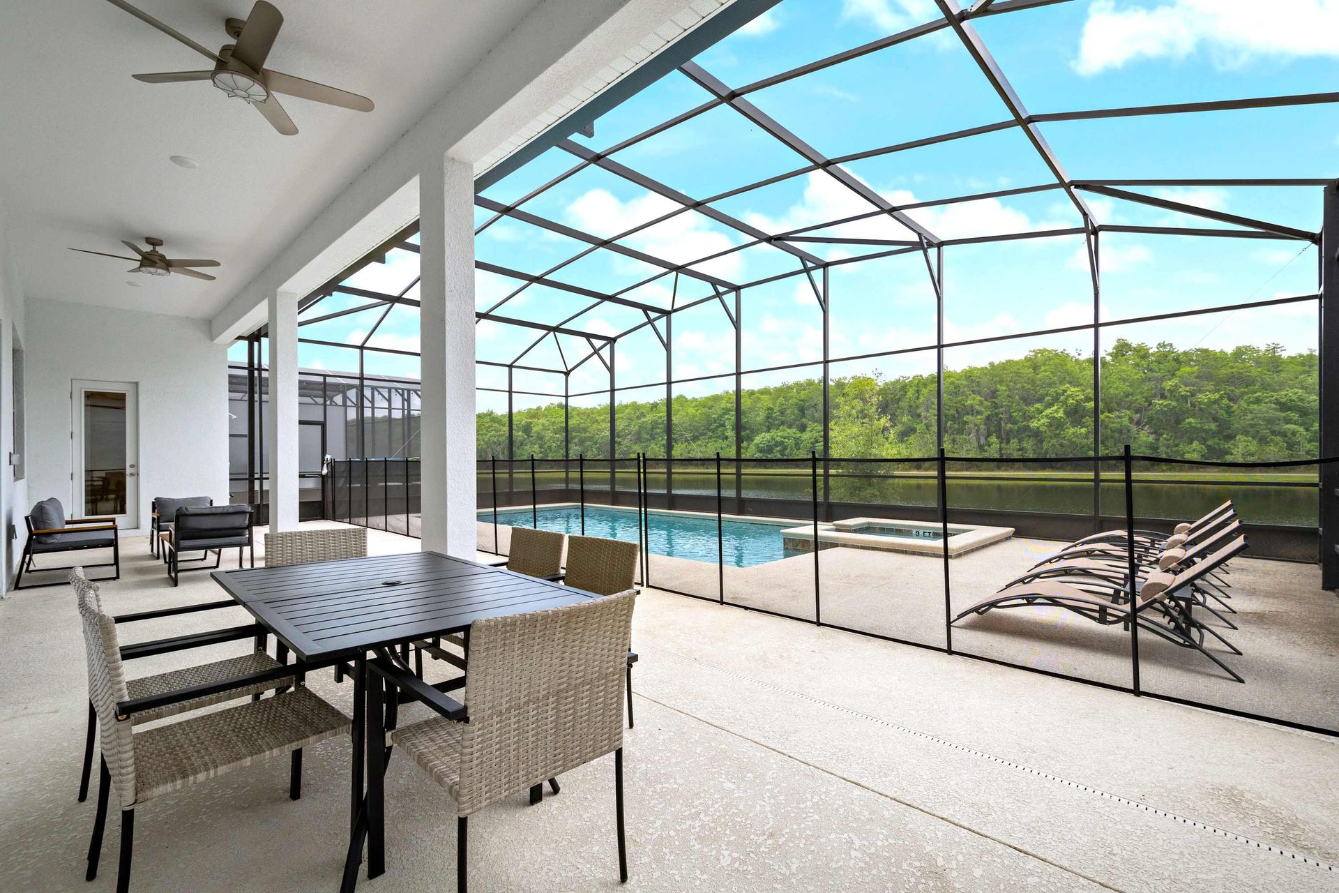 Spacious screened patio with pool, dining area, lounge chairs, and nature views
