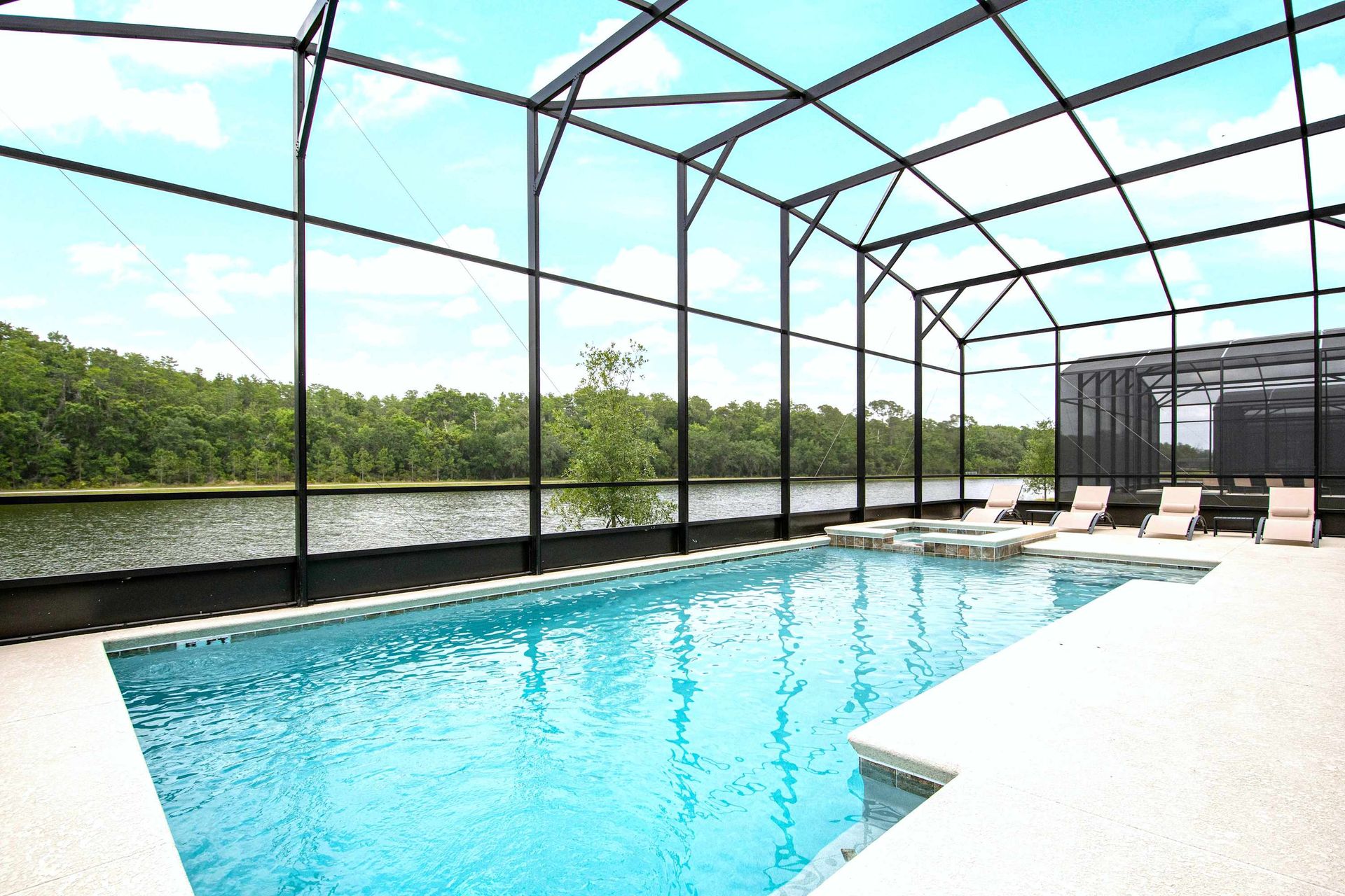 Lakeside screened pool with spa, surrounded by nature and relaxing loungers
