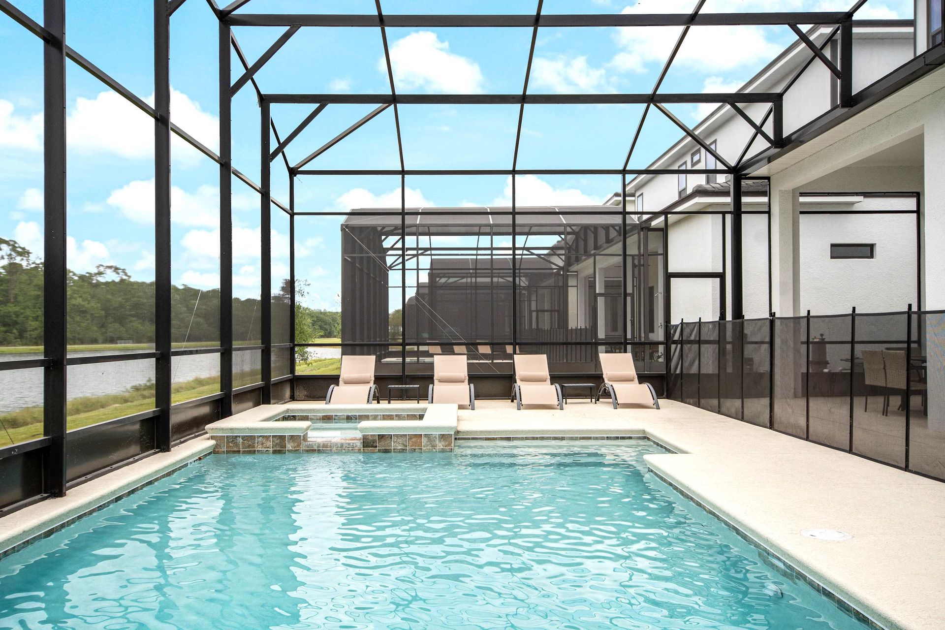 Lakeside screened pool with spa, surrounded by nature and relaxing loungers
