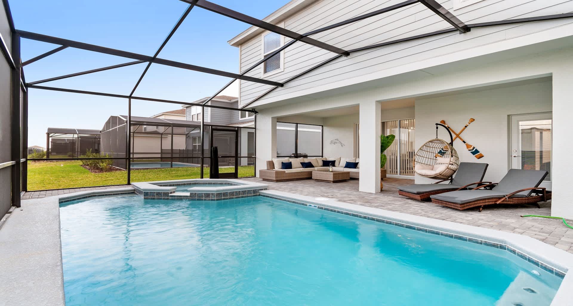 Private screened-in pool with spa, lounge chairs, and covered outdoor seating area.
