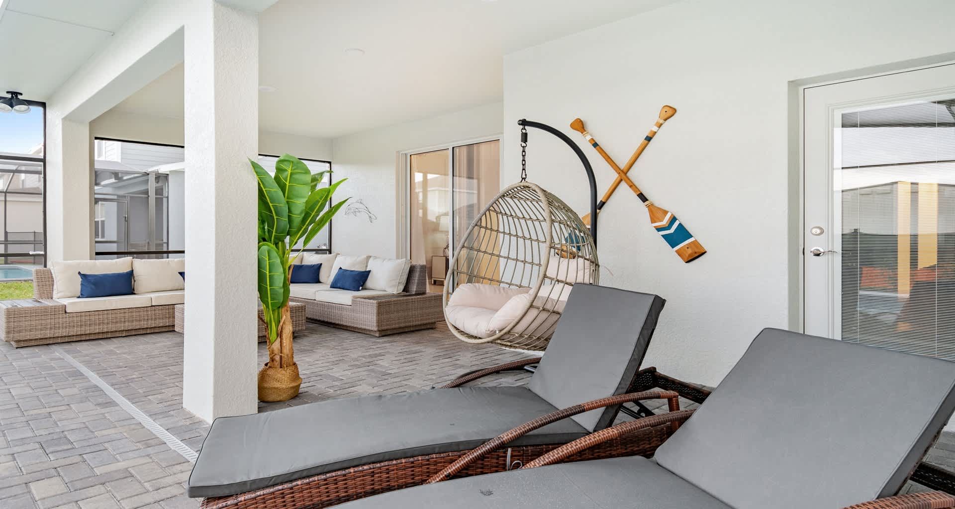 Relaxing covered patio with lounge chairs, hanging swing, and cozy outdoor seating.
