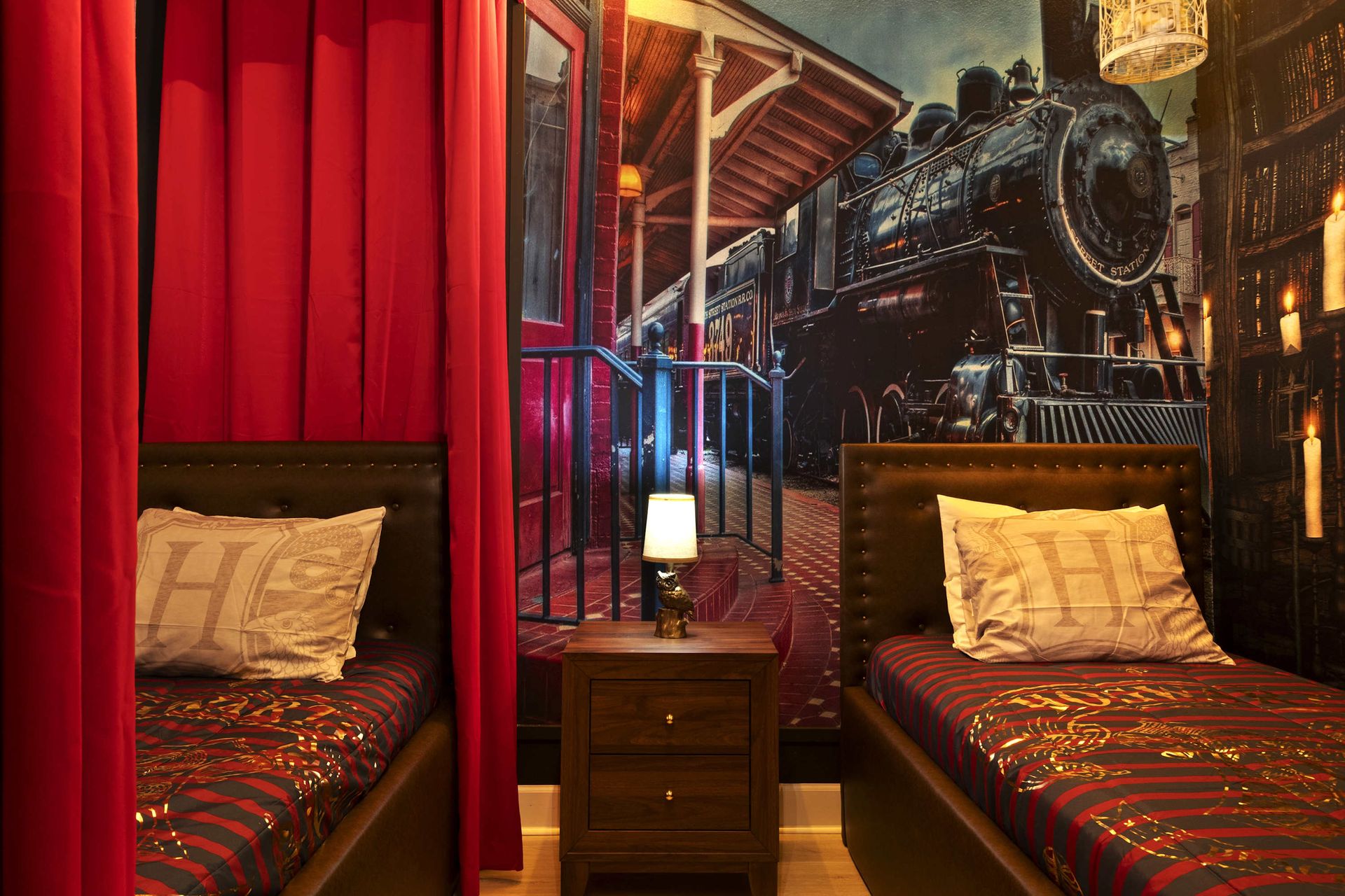 All aboard! Twin beds with a Hogwarts Express mural and red curtains.