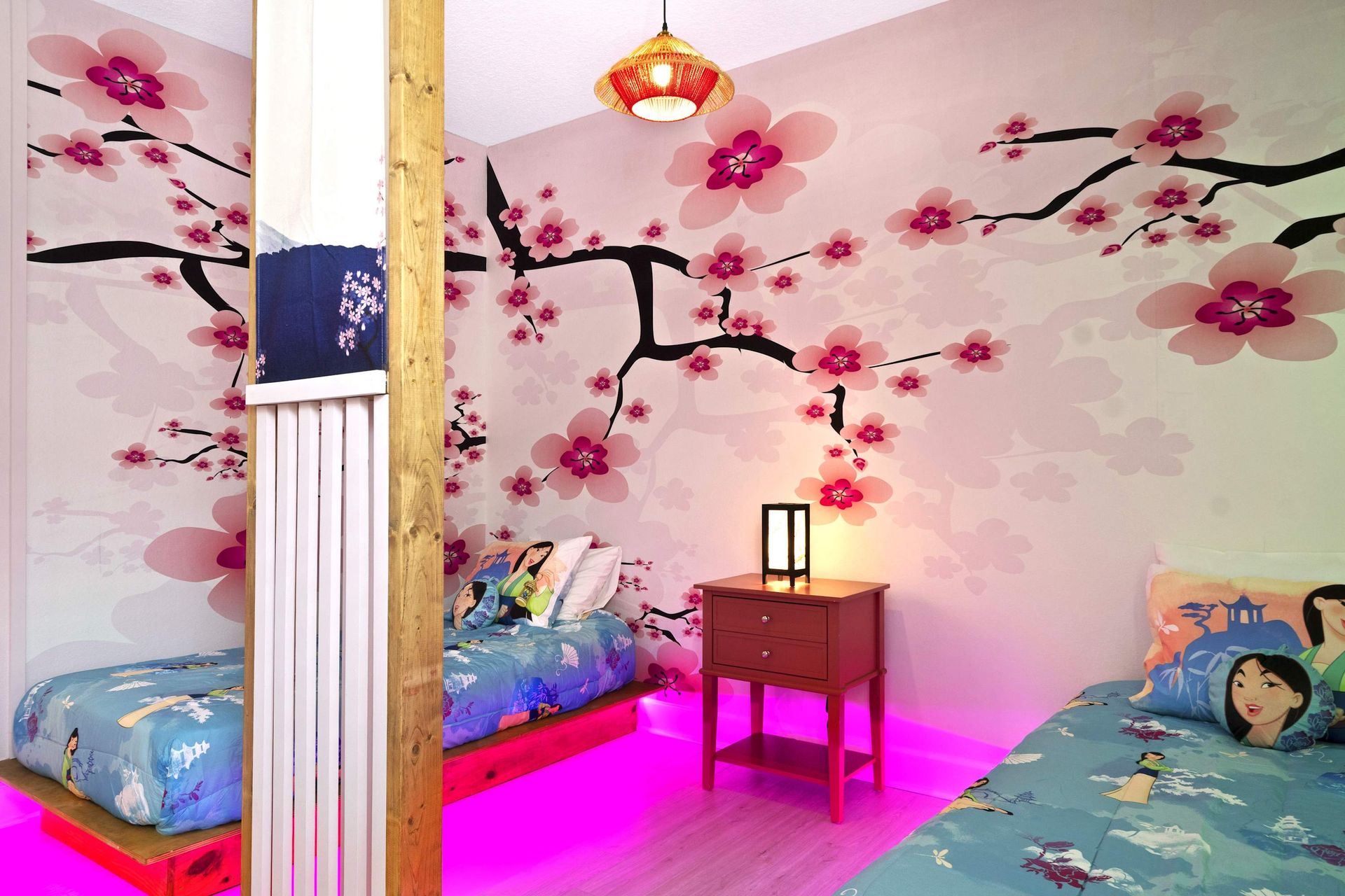Cherry blossom mural and twin beds with magical pink floor lighting.