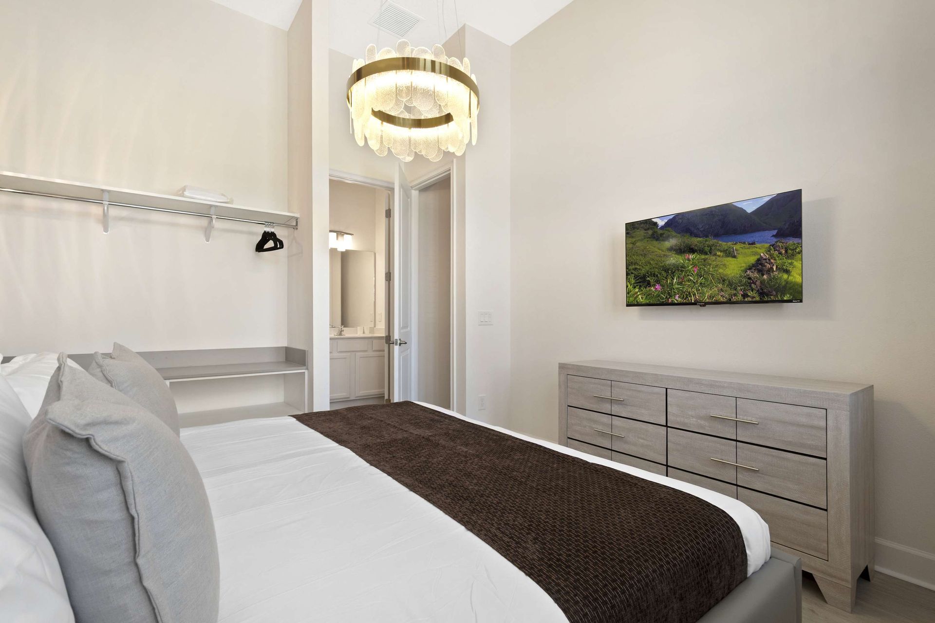 Bright, modern queen room with chic chandelier and flat-screen TV. 