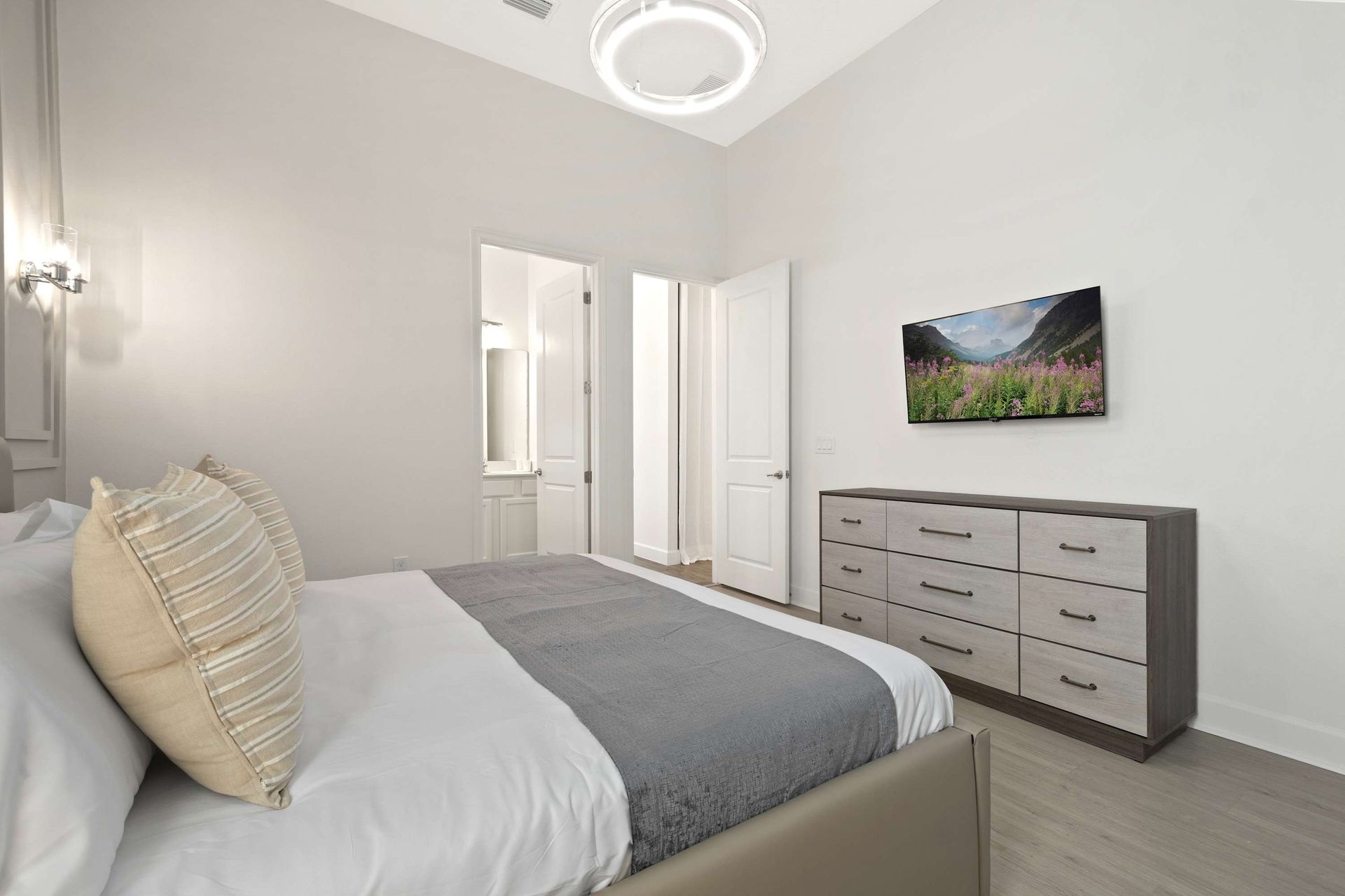 Airy master suite with vaulted ceiling, king bed, and modern dresser.
