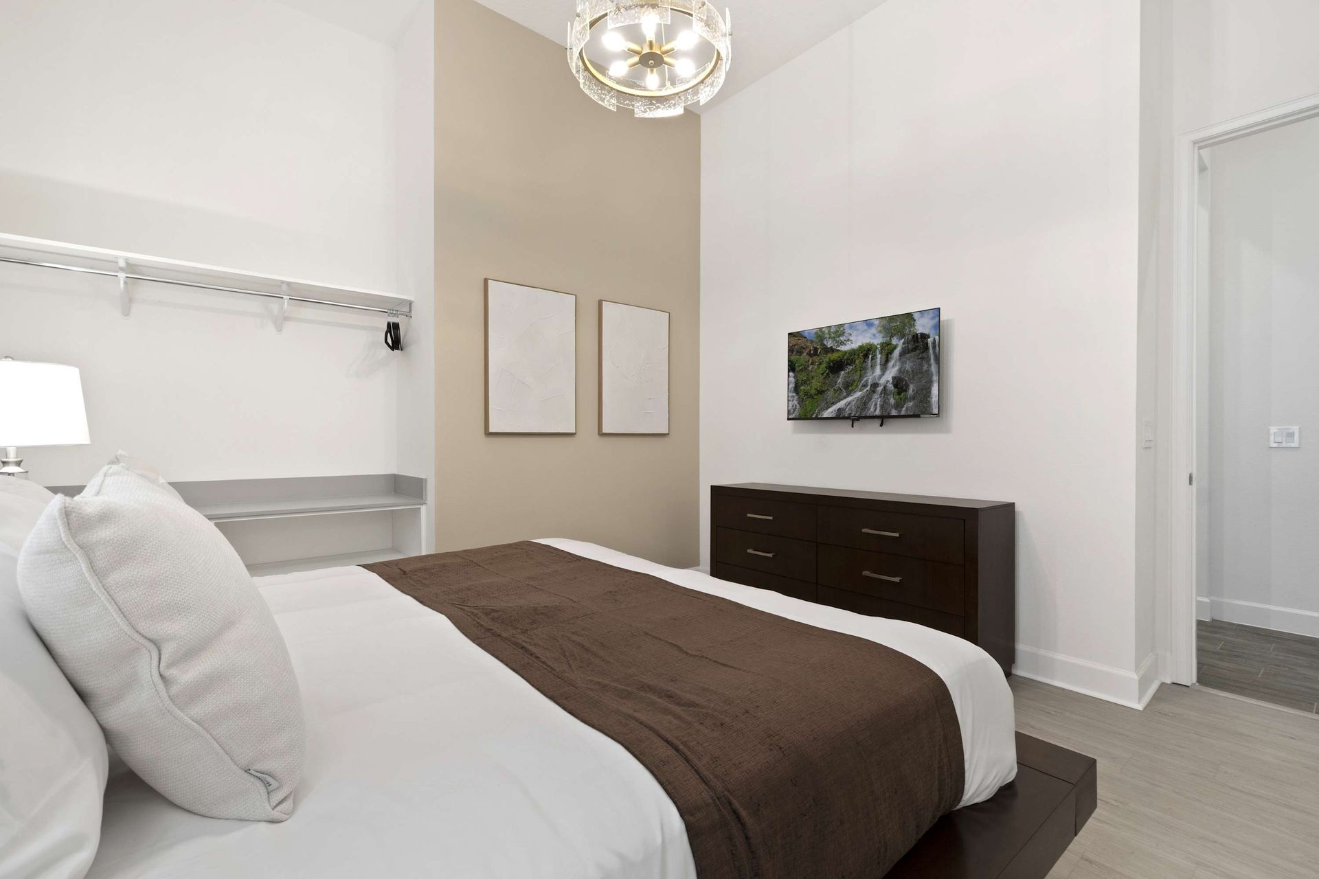 High ceilings, modern light, and accent wall in this stylish queen room. 