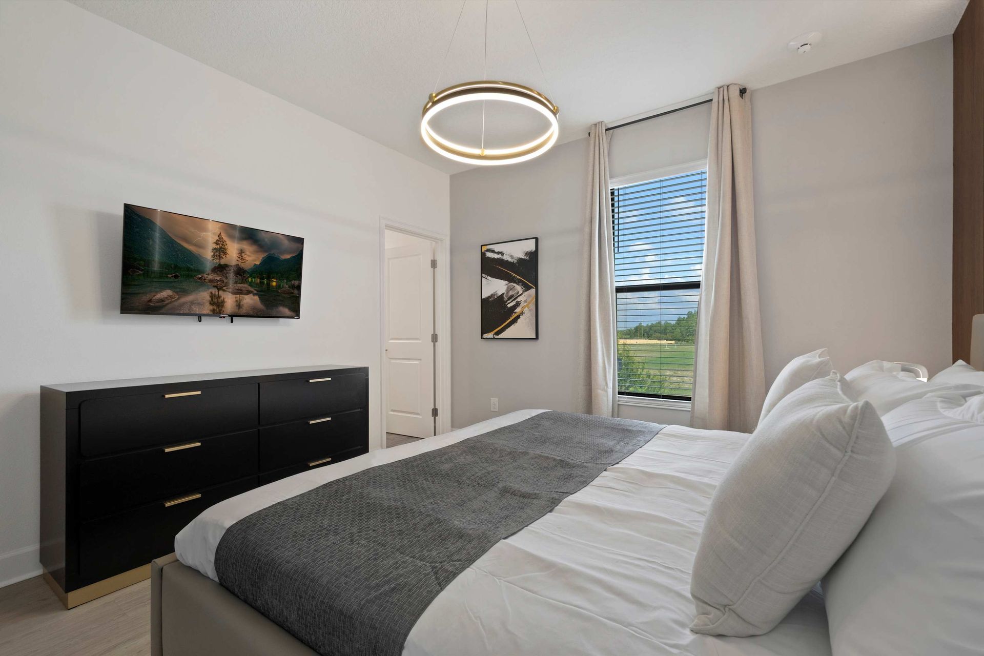 Sleek modern suite with king bed, wall-mounted TV, and designer lighting.
