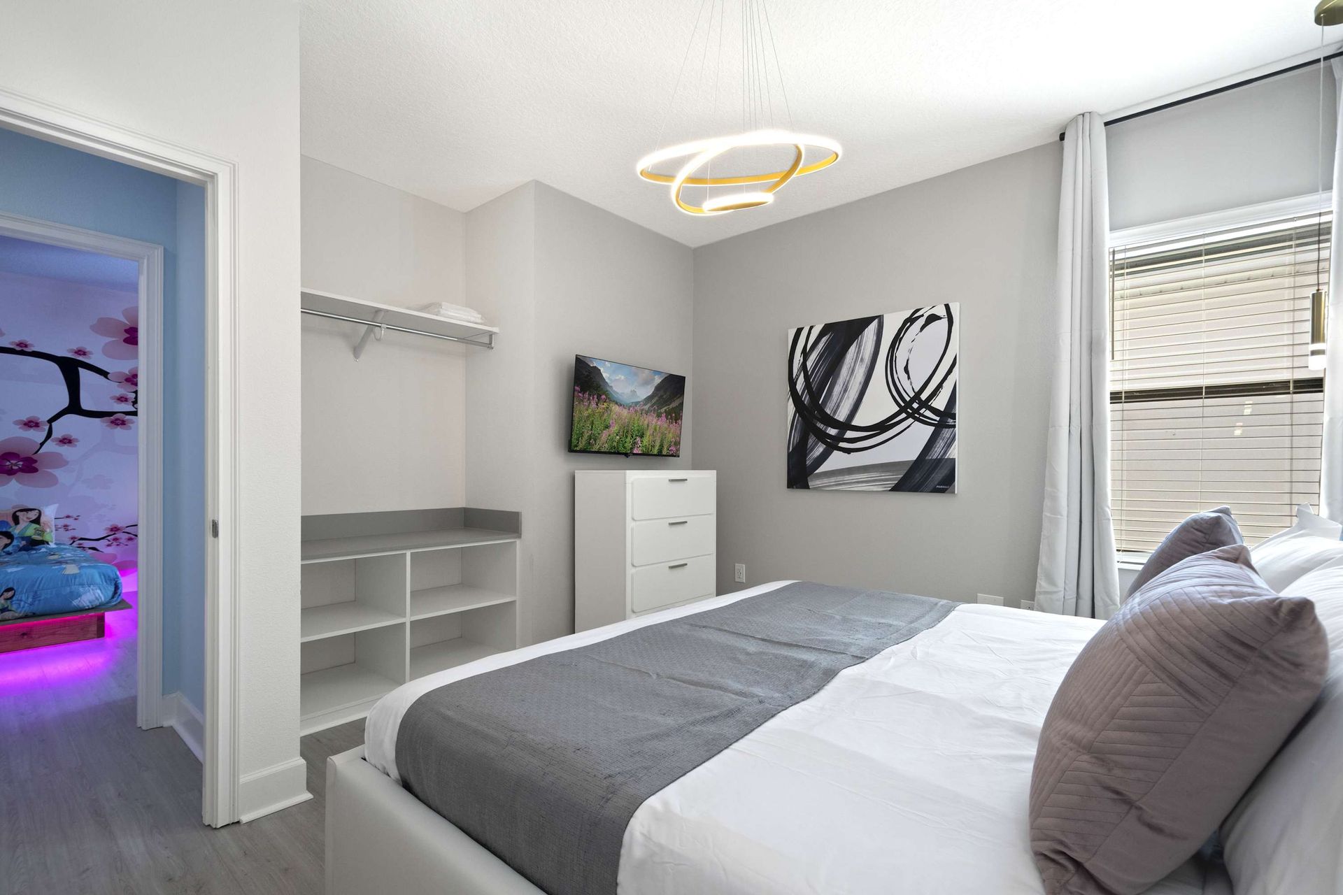 Sleek queen room with modern art, TV, and open closet storage. 