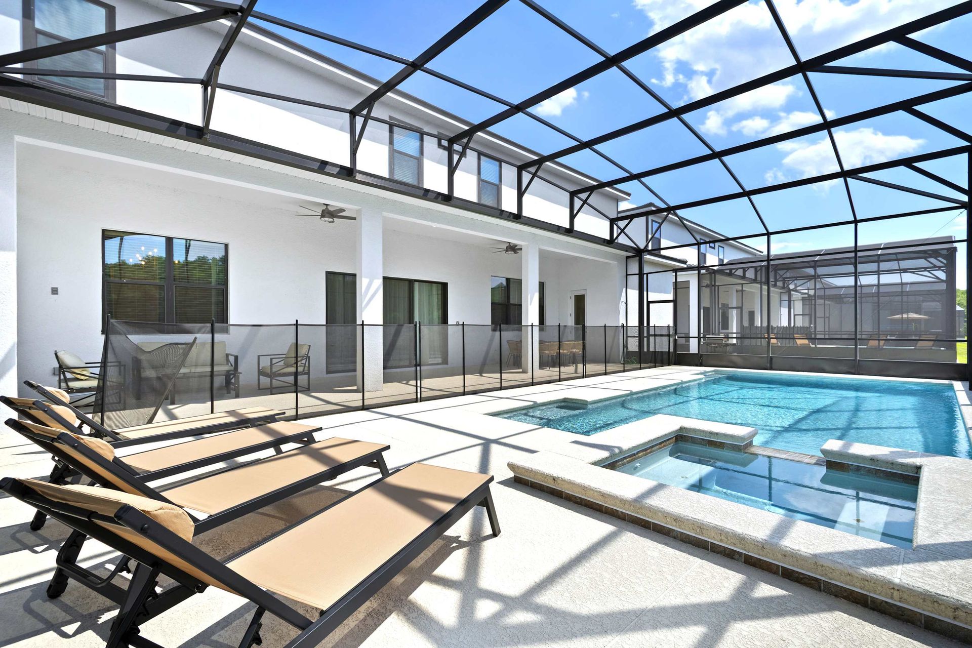 Private screened pool and hot tub with a safety fence and sun deck. 