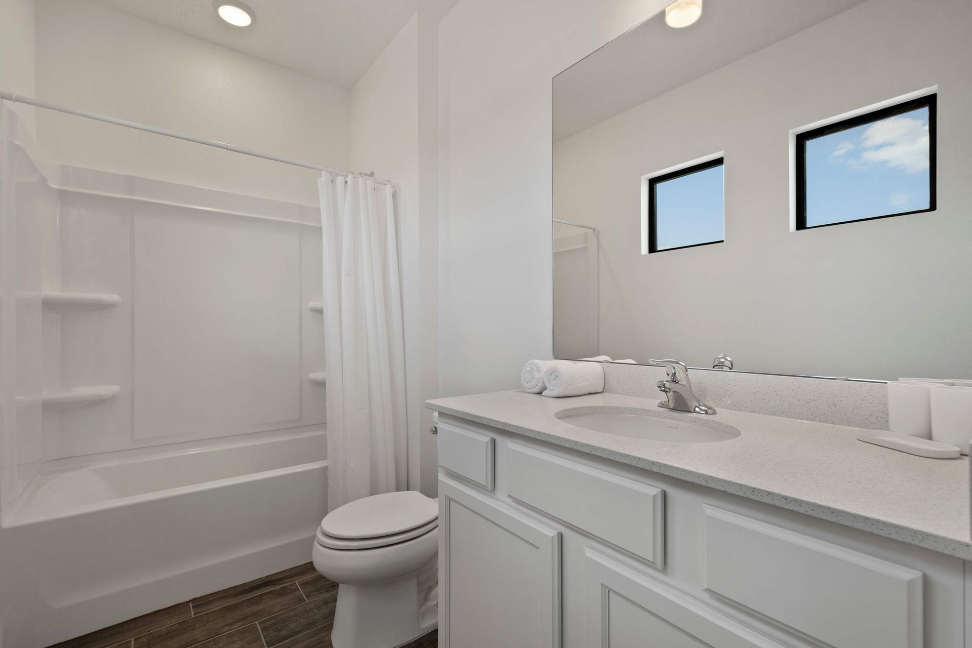 Clean and modern full bath with tub/shower and bright white vanity.