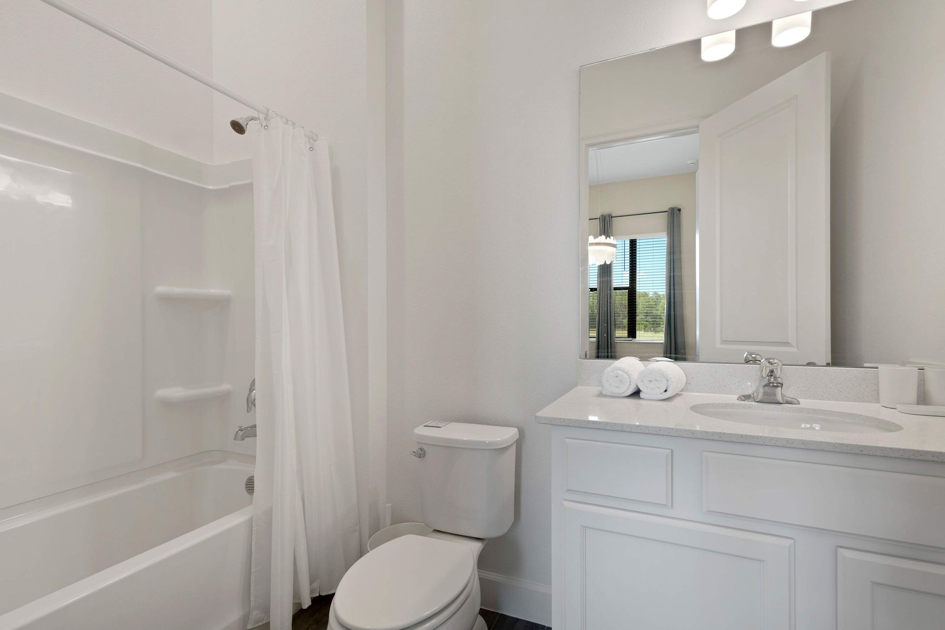 Clean full bath with white vanity, tub/shower combo, and bright light.