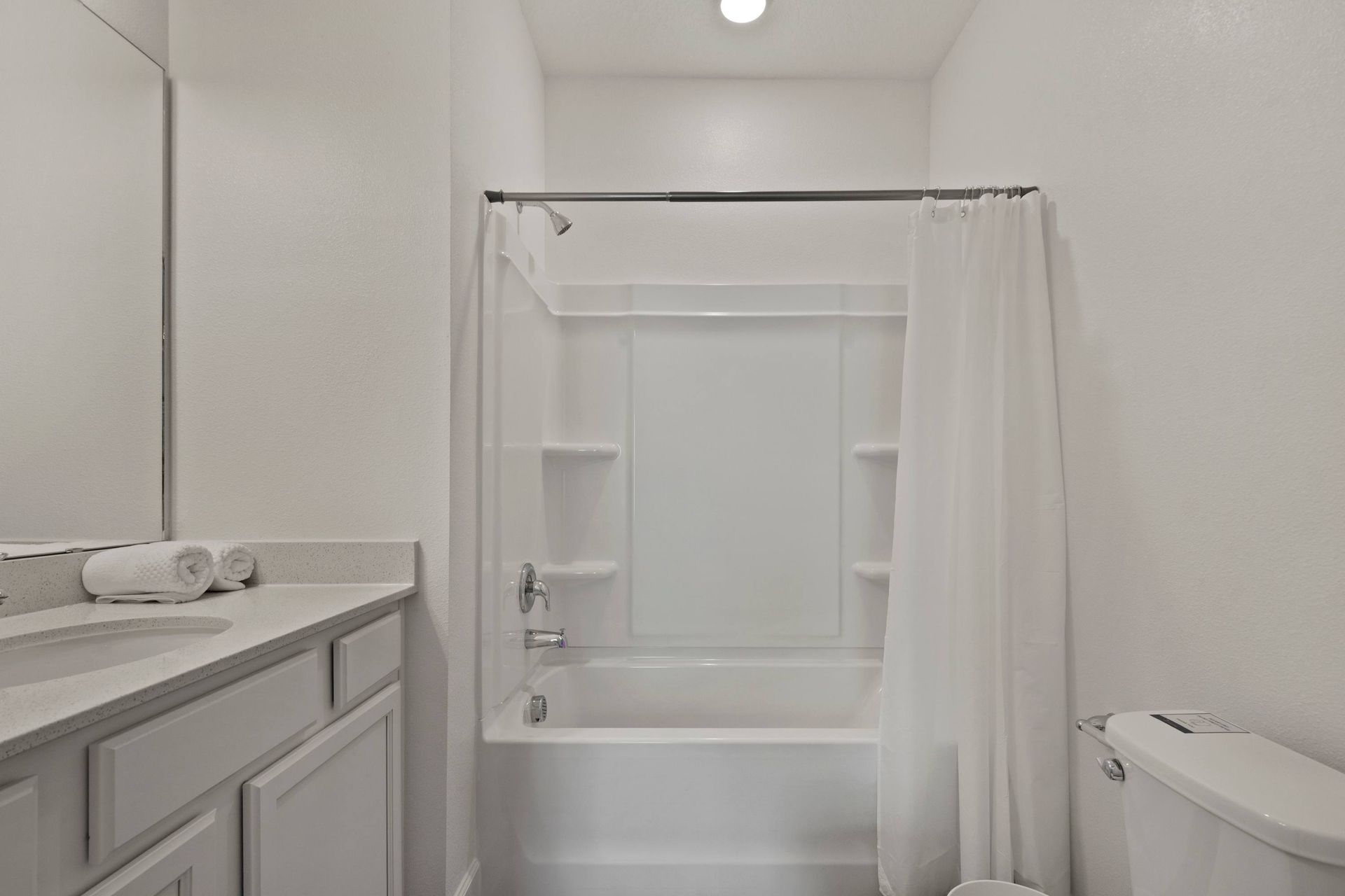 Crisp, clean bathroom with modern white vanity and tub/shower combo.