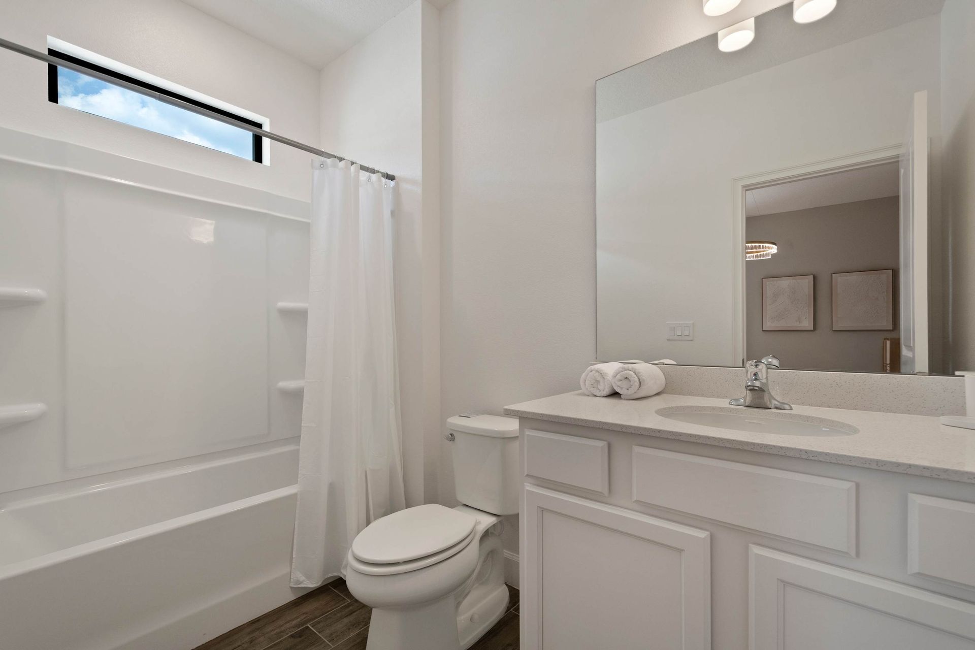 Full bath with tub/shower combo and modern white cabinetry.