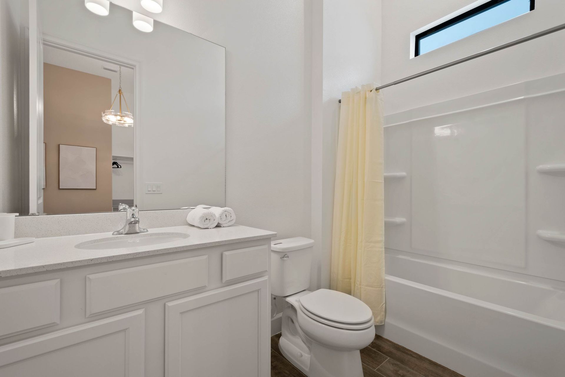 Bright full bathroom with large vanity and ample natural light. 
