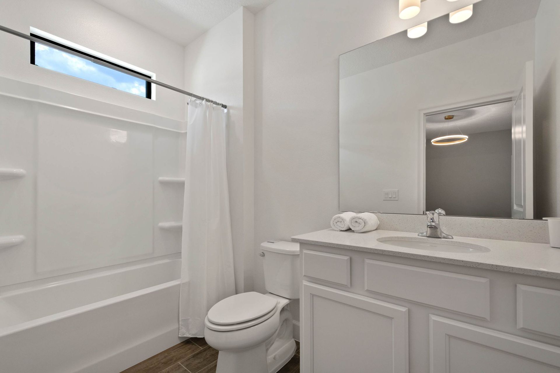 Bright, modern full bathroom with tub and large mirror. 