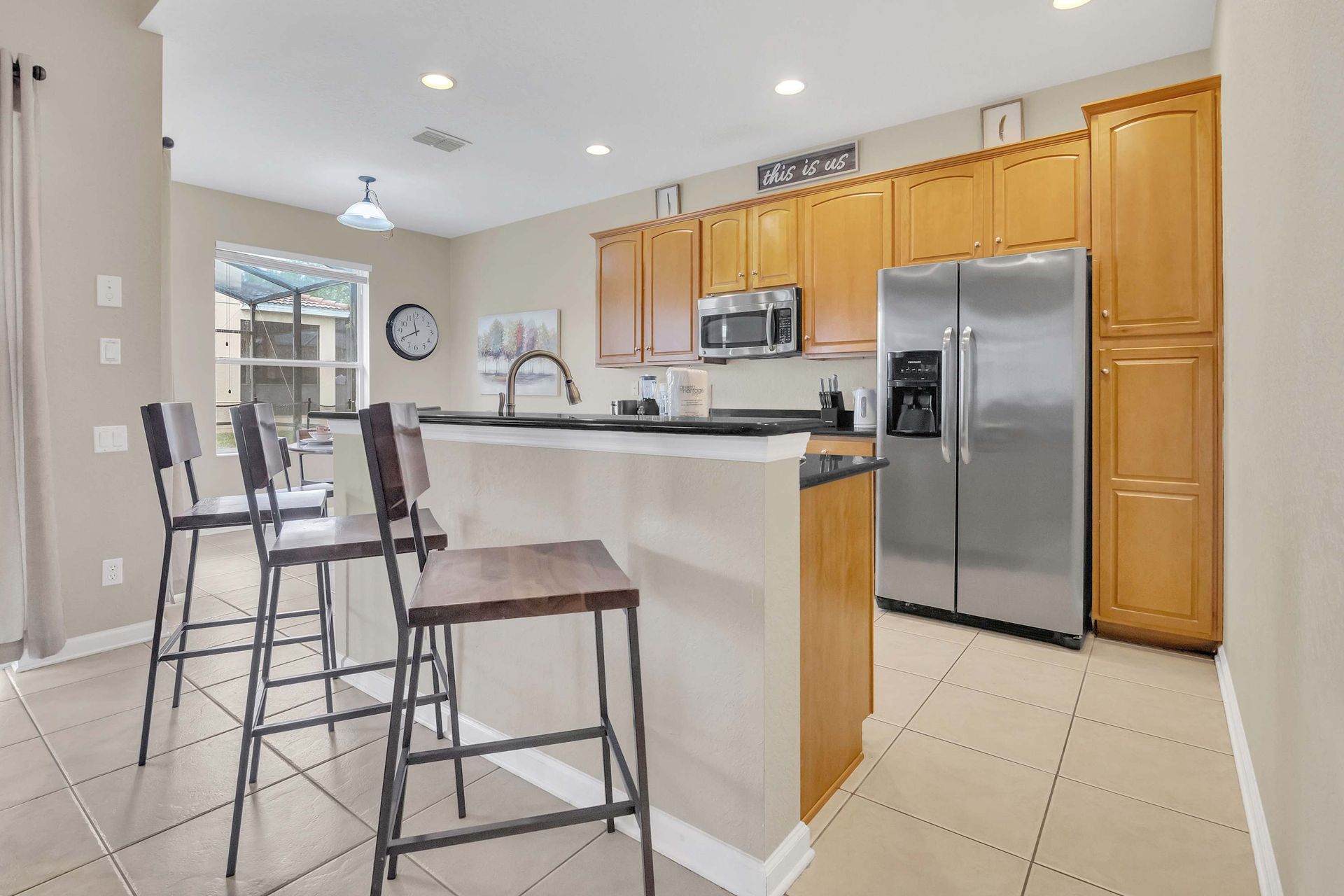 Bright kitchen, ample cabinetry, and breakfast bar overlooking the pool.