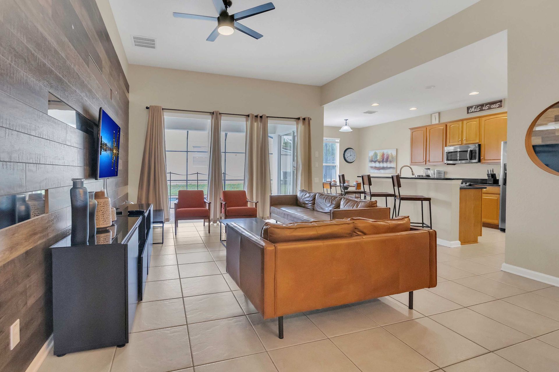 Open-concept living: rich leather, wood accent wall, and bright kitchen flow.