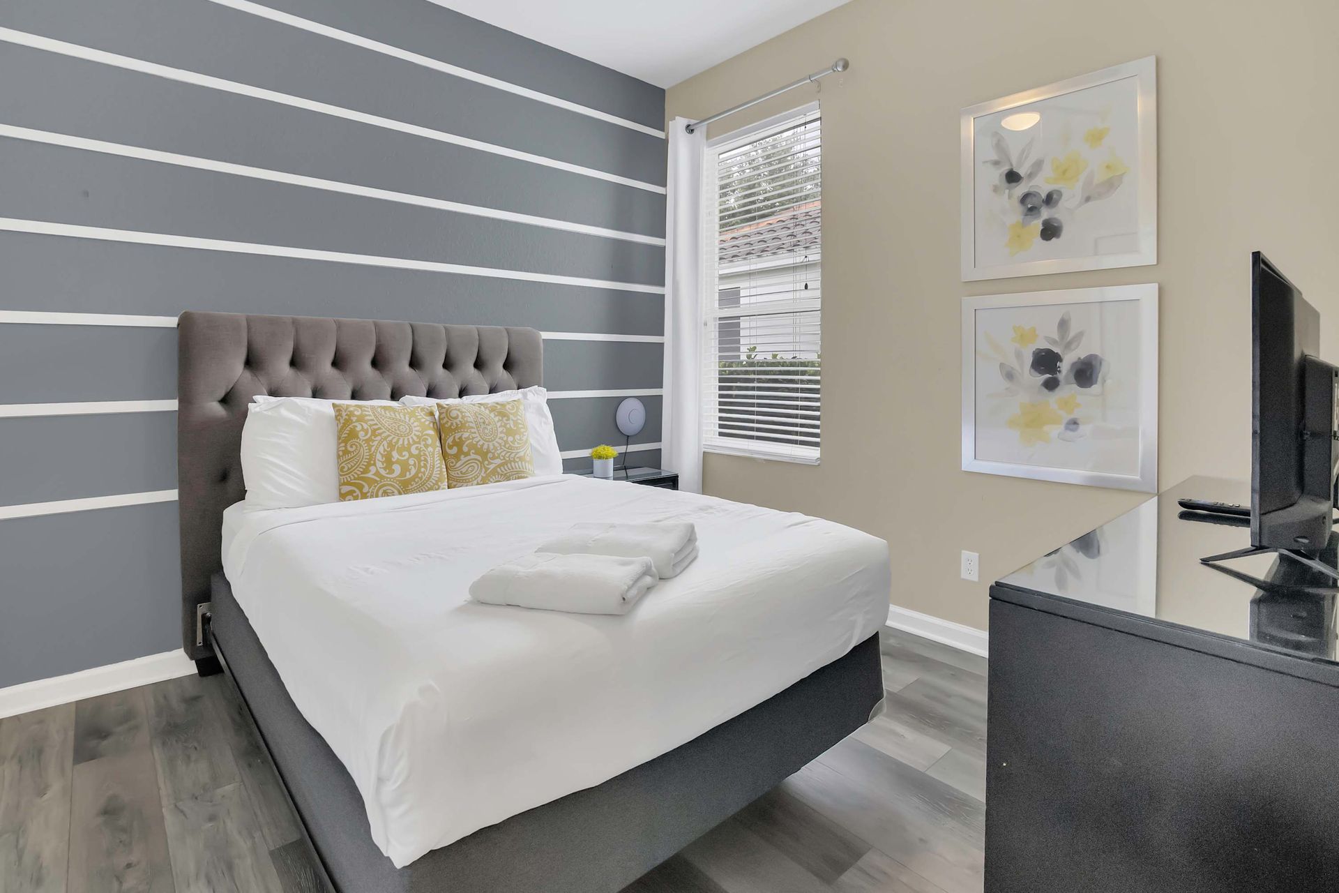 Comfy queen bed with modern gray and white striped wall.
