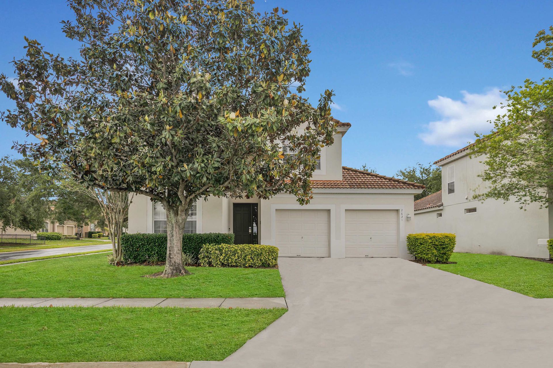 Lovely Florida home with a tile roof, two-car garage, and lush yard.