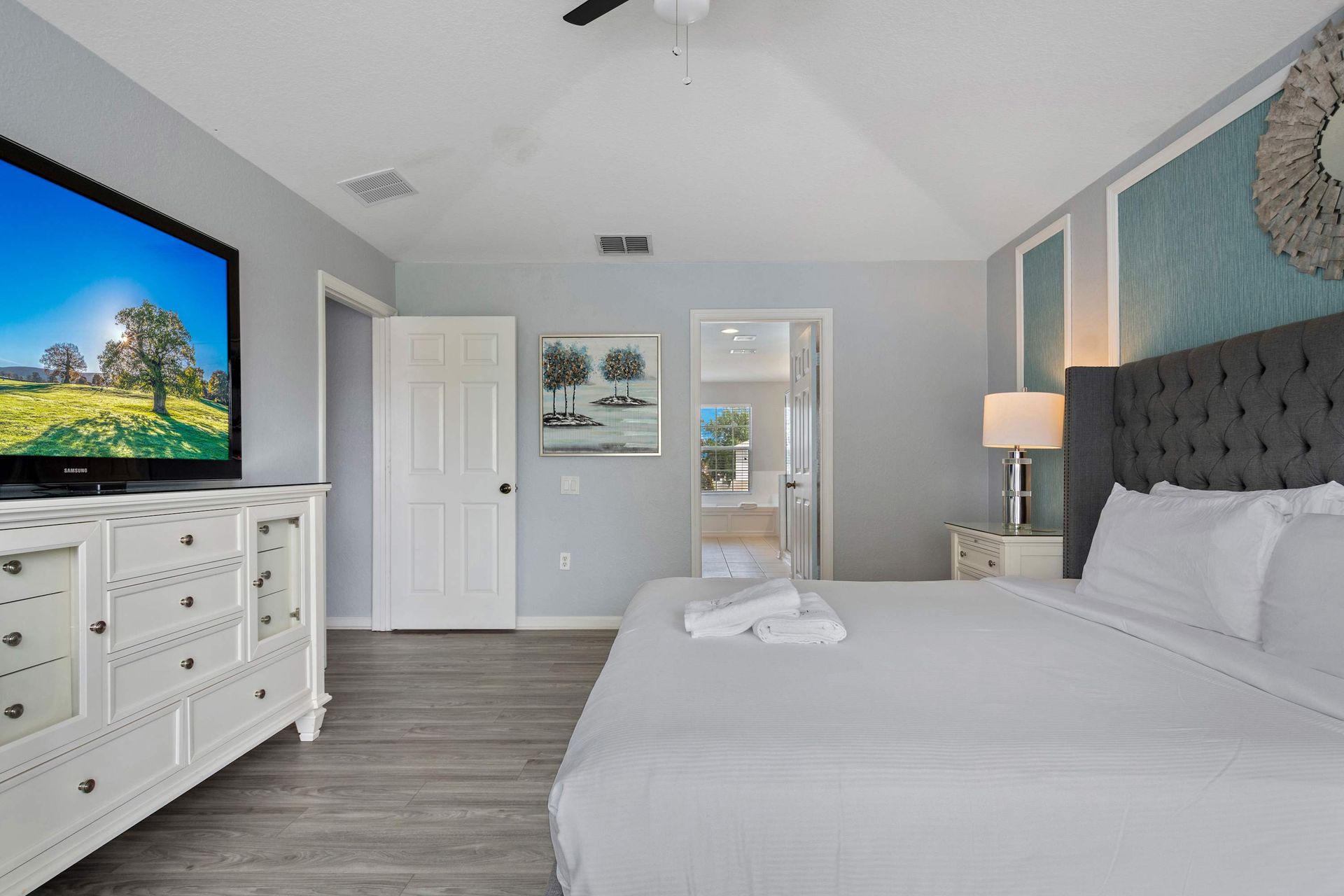 Bright master bedroom with king bed, large TV, and convenient in-room crib setup
