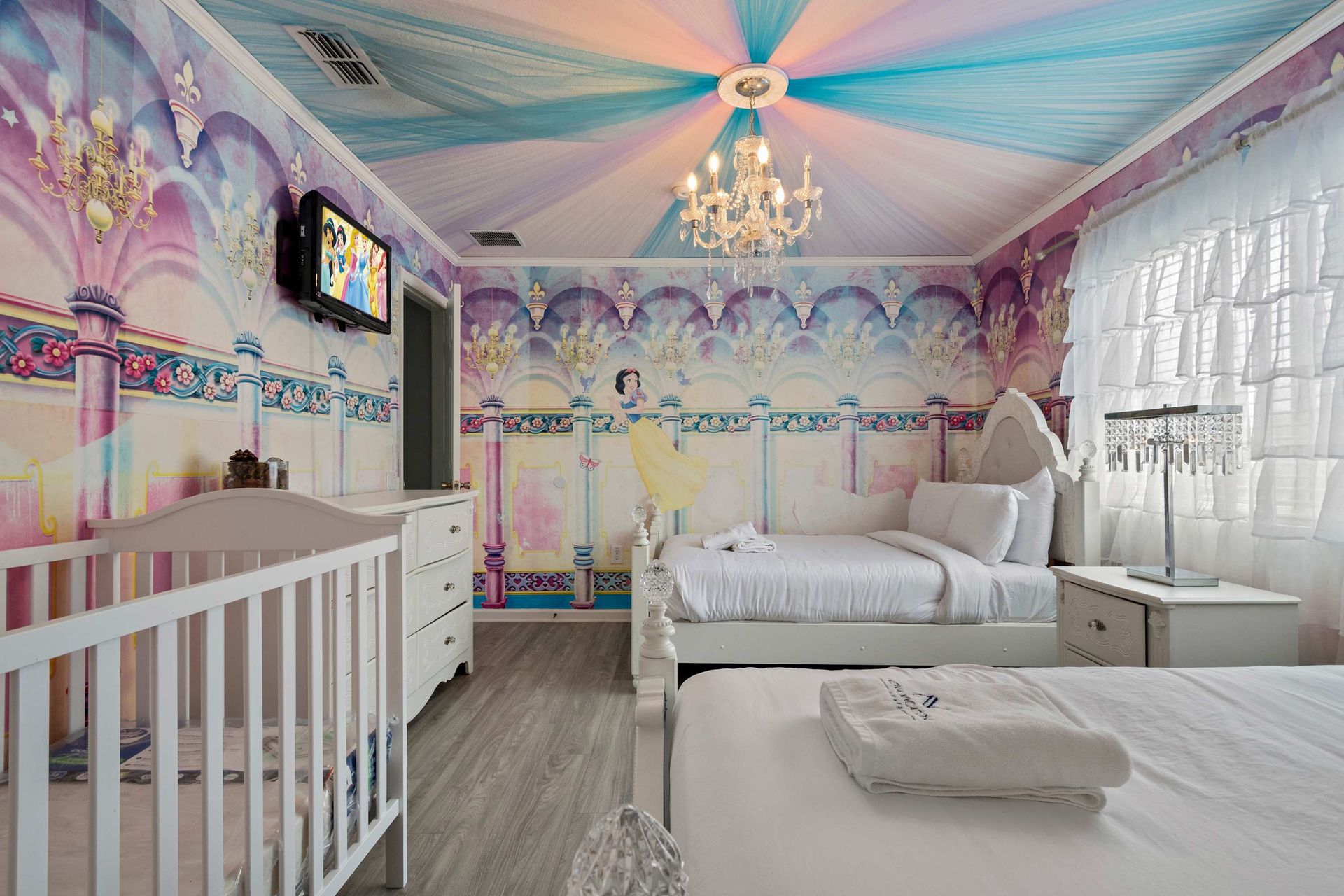 Enchanting princess-themed room with chandelier, dreamy murals, and royal beds
