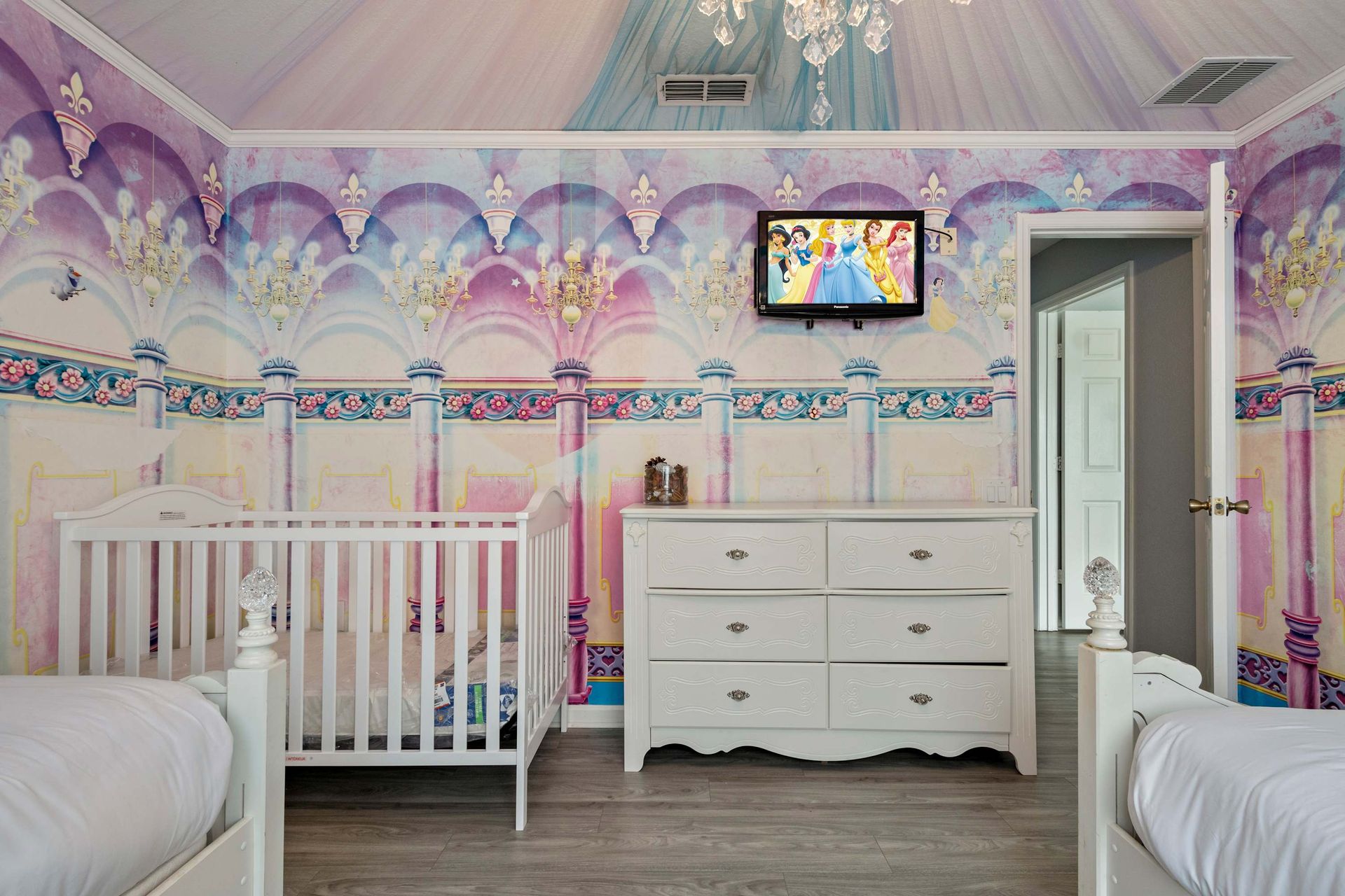 Enchanting princess-themed room with chandelier, dreamy murals, and royal beds
