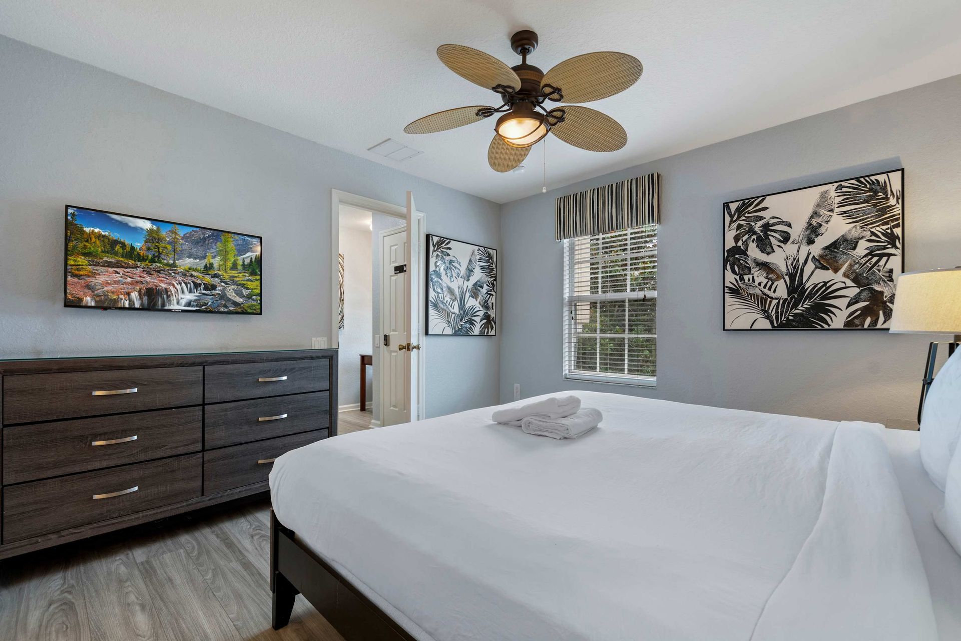 Chic king bedroom with bold art, striped accent wall, and plenty of natural light
