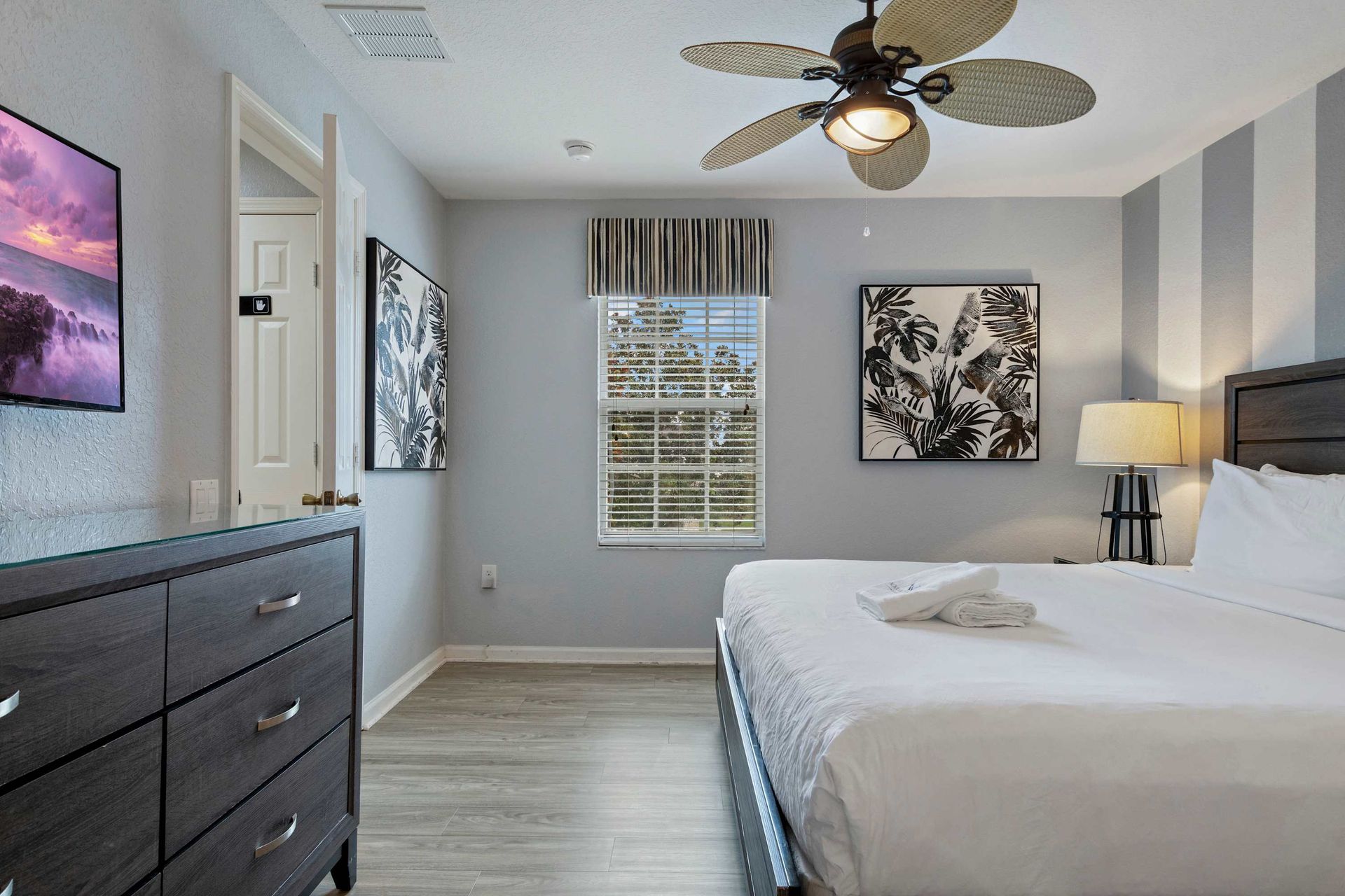 Chic king bedroom with bold art, striped accent wall, and plenty of natural light
