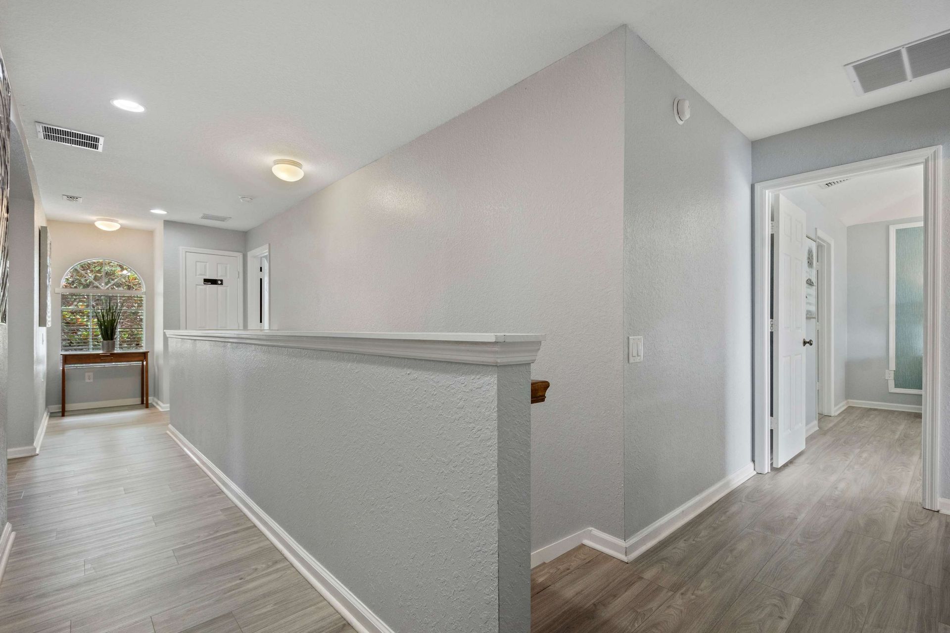 Bright upstairs hallway with modern flooring, neutral tones, and elegant trim details
