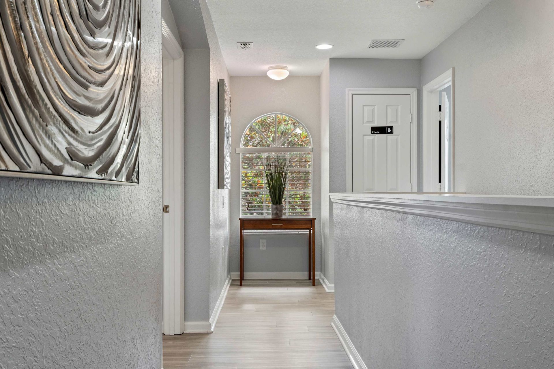 Elegant hallway with arched window, stylish decor, and soft natural lighting throughout
