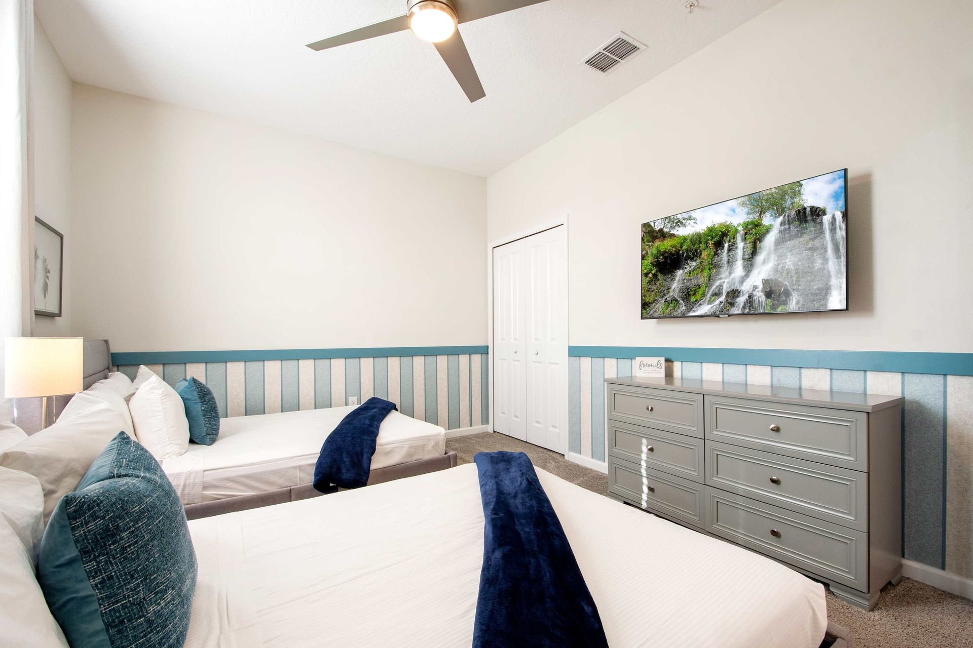 Airy room with nautical stripes, soft gray tones, and ceiling fan.